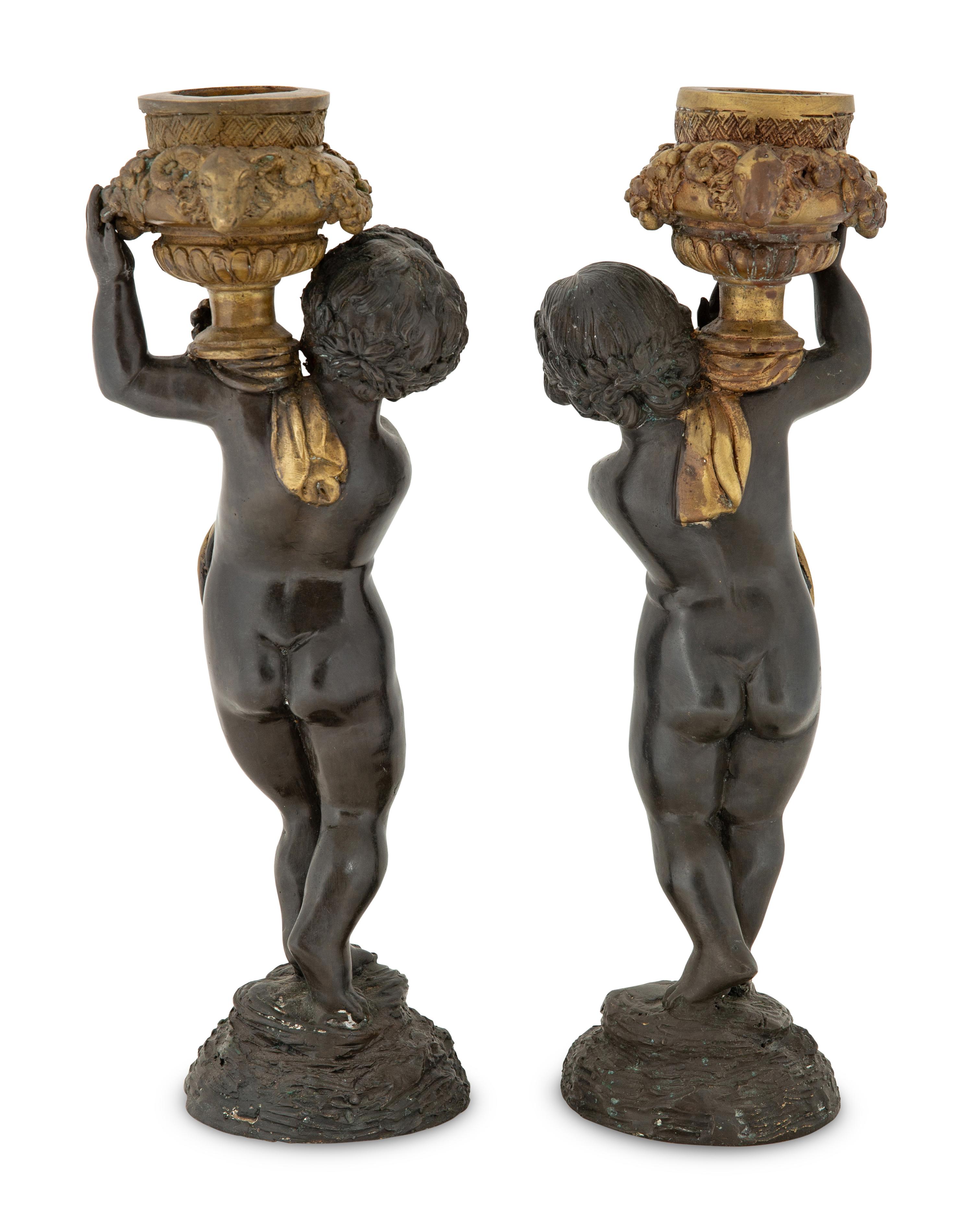 A Pair of Parcel Gilt Cast Metal Putti Candlesticks