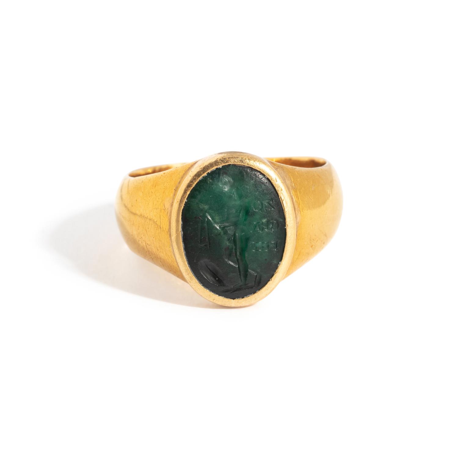 A Roman Gold and Plasma Finger Ring with a Figure Holding Tools and an Inscription