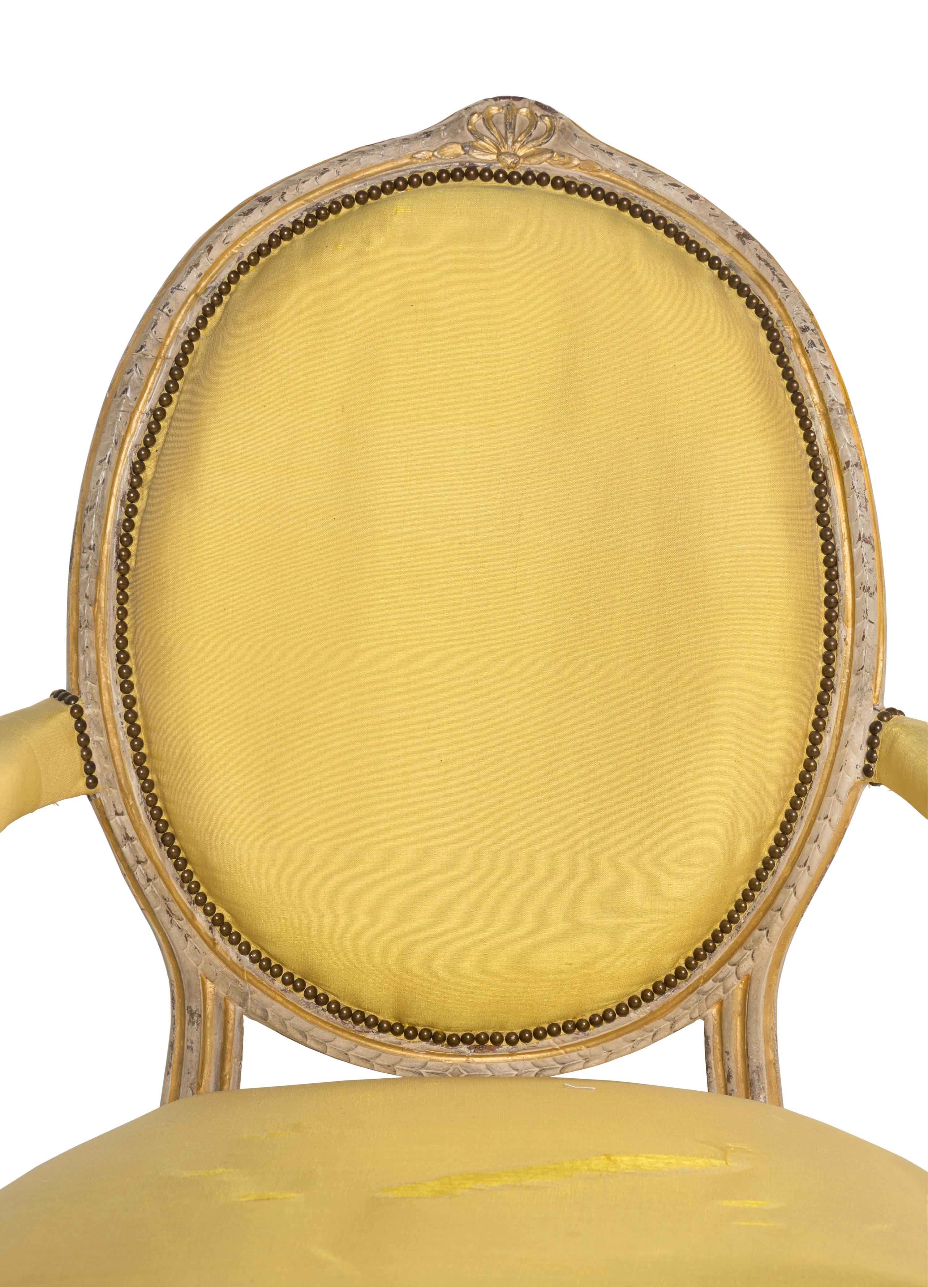 A Pair of George III Carved, Grey-Painted and Parcel Gilt Armchairs