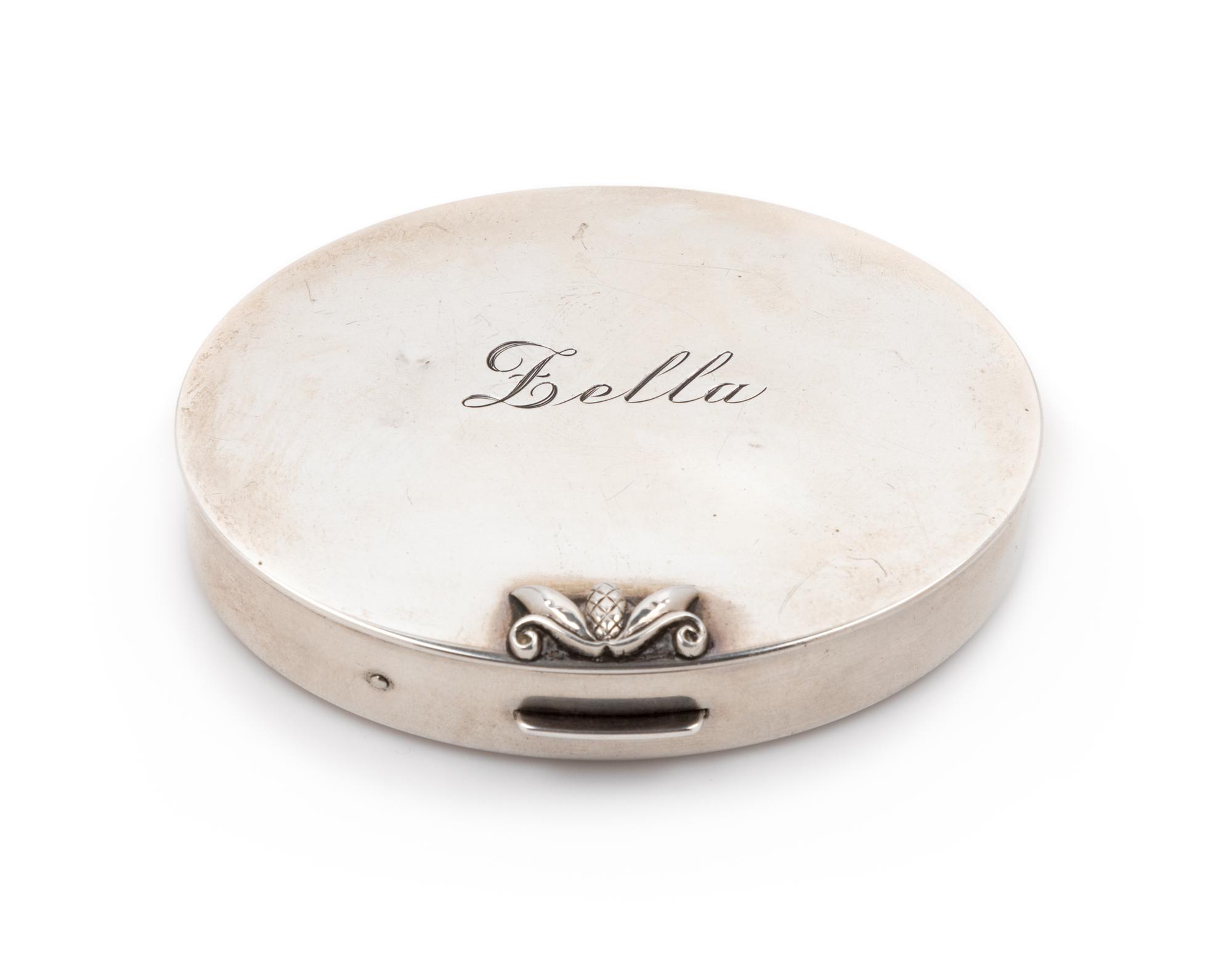An American Silver Compact, Georg Jensen Inc., New York, NY, Circa 1940, or oval form, the lid with an engraved name and applied foliat