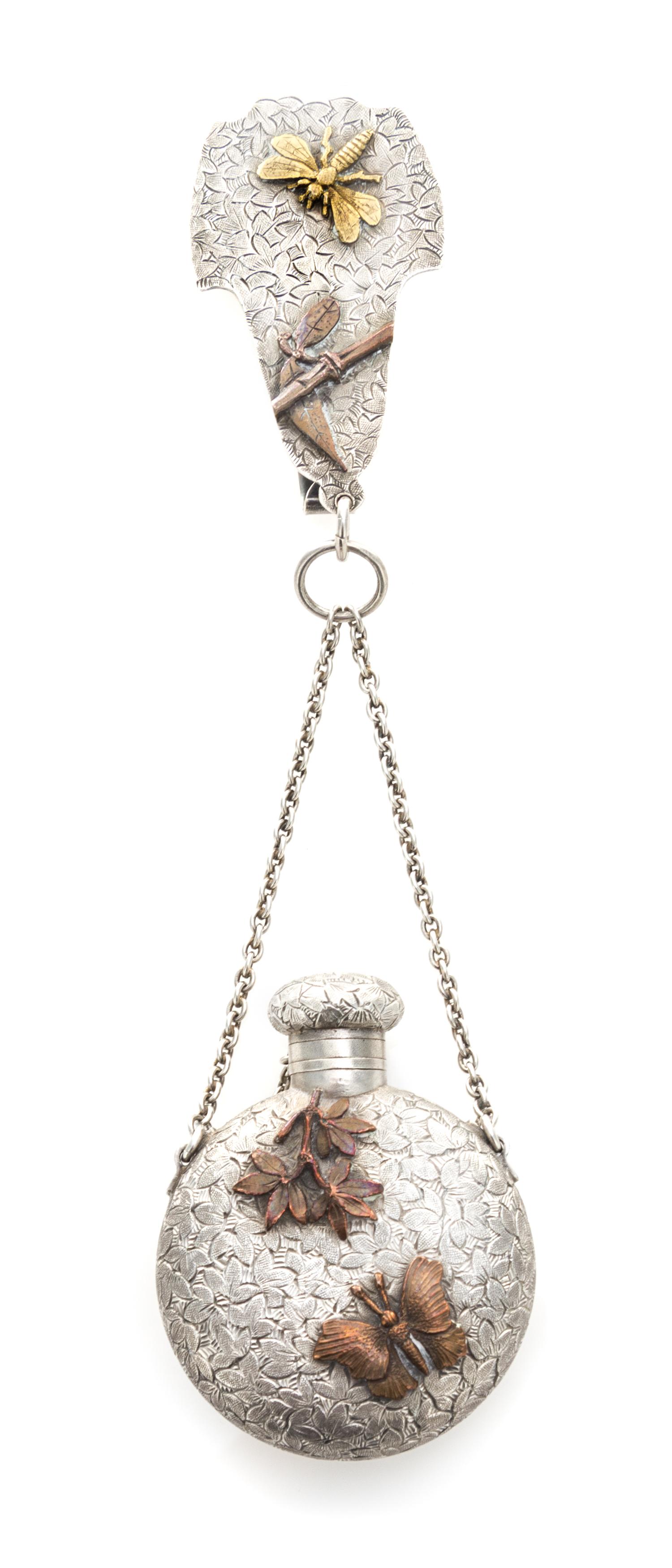 An American Silver and Mixed Metal Perfume Bottle, Dominick & Haff, New York, NY,, the bottle suspended from a chain to a central clip,