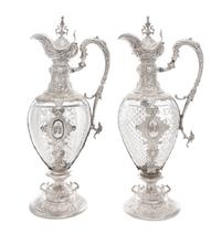 A Pair of Continental Silver Mounted Cut Glass Claret Jugs, Likely German, 19th Century, each having an urn finial above the hinged lid