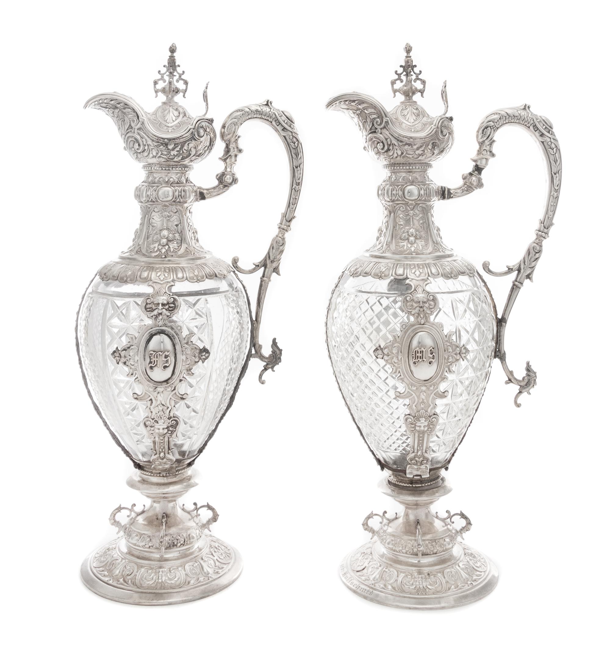 A Pair of Continental Silver Mounted Cut Glass Claret Jugs, Likely German, 19th Century, each having an urn finial above the hinged lid