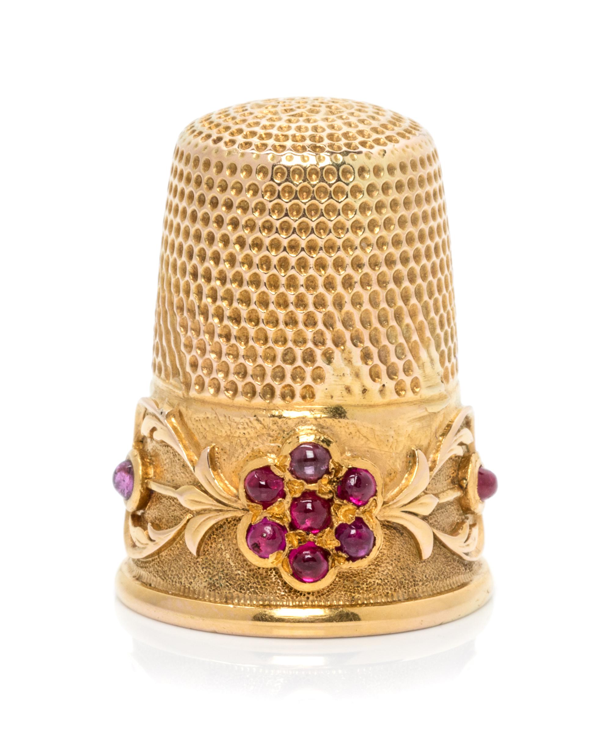 A Continental Yellow Gold and Ruby Thimble, , the knurled top and body surmounting a floral and foliate decorated band, the floral elem