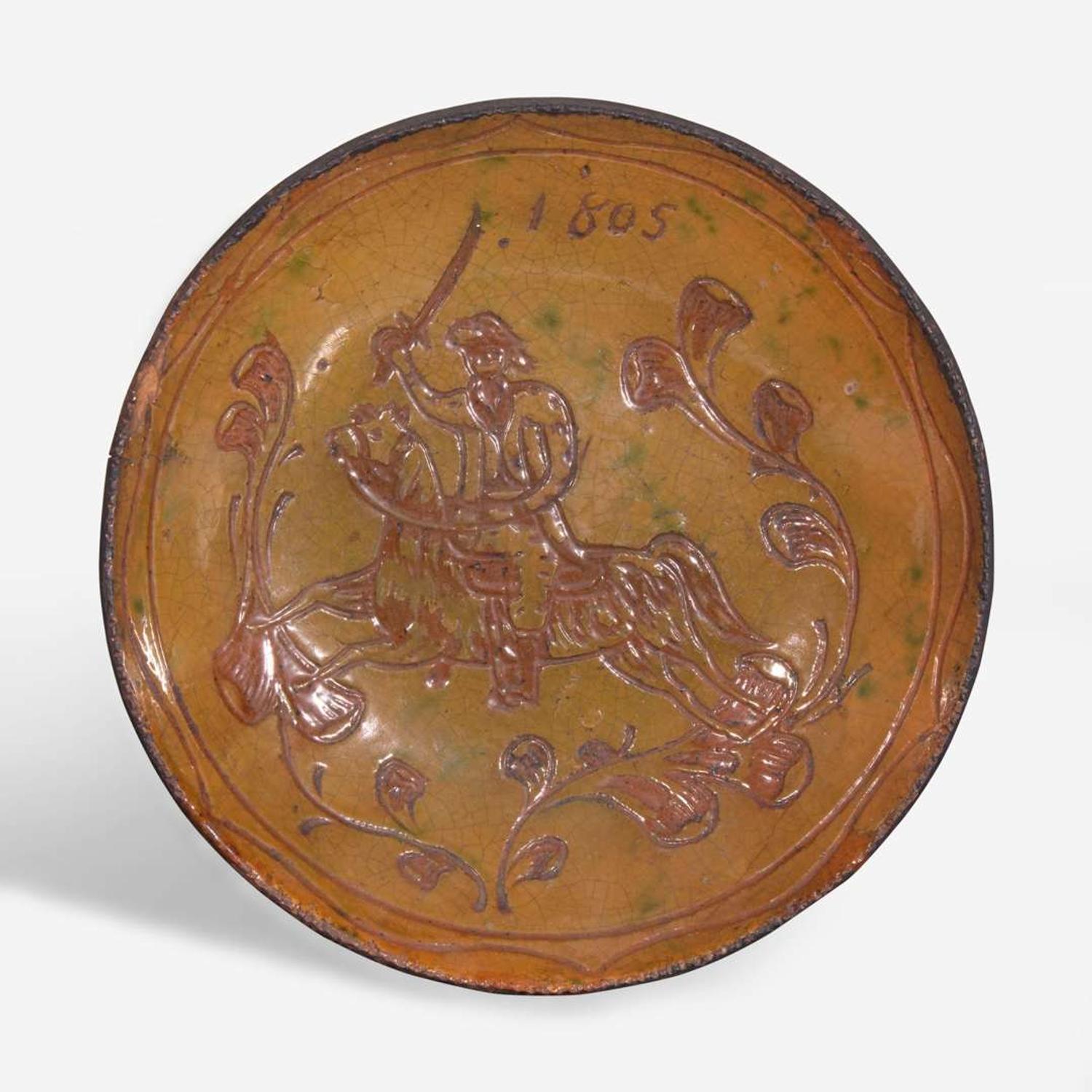 A glazed sgraffito-decorated redware plate depicting a horse and cavalier attributed to Jacob Medinger (1856-1932), Montgomery County, PA