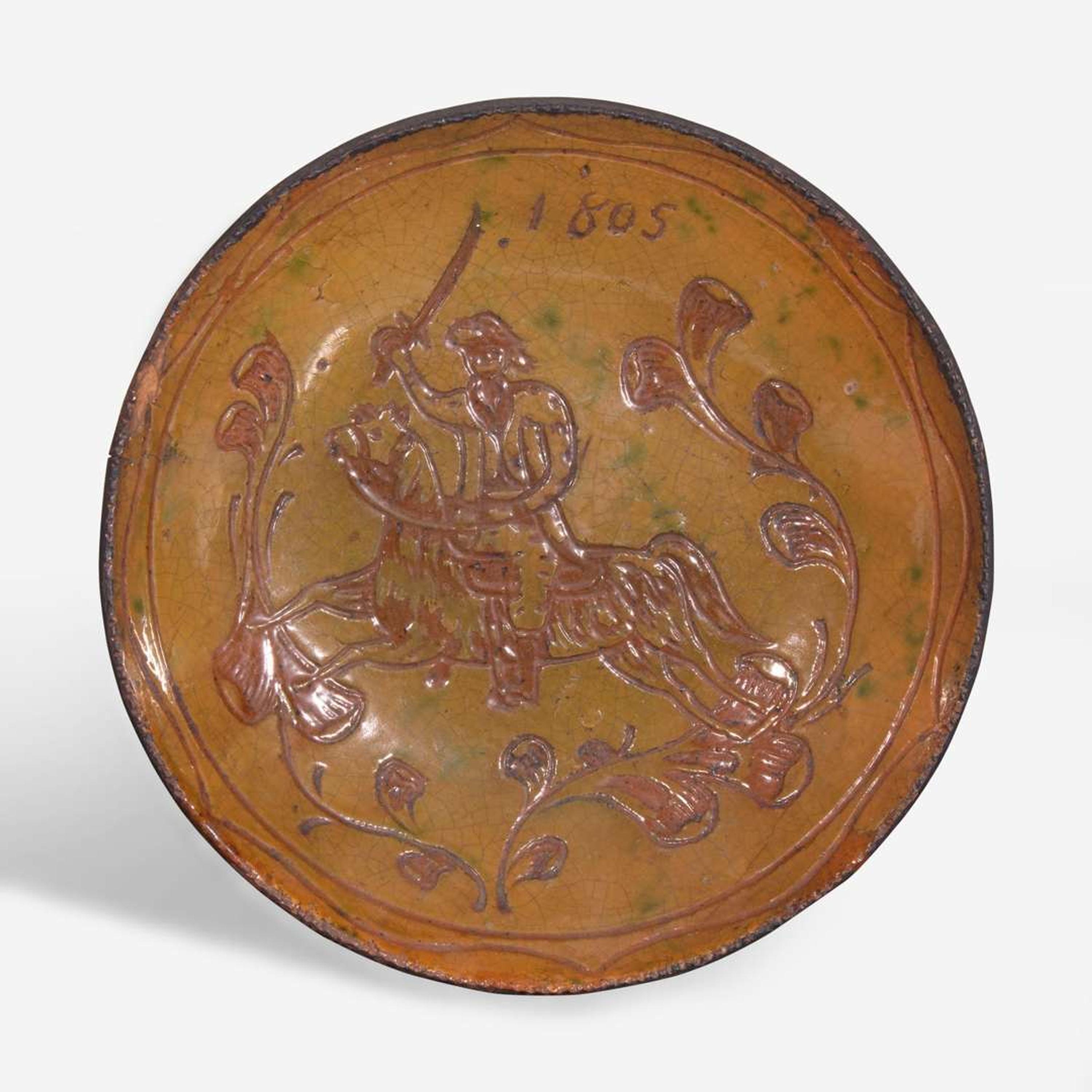 A glazed sgraffito-decorated redware plate depicting a horse and cavalier attributed to Jacob Medinger (1856-1932), Montgomery County, PA