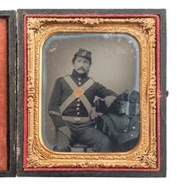 [CIVIL WAR]. Sixth plate ruby ambrotype portrait of a 71st New York State Militia private posed in uniform with his knapsack, rolled blanket, and great coat sitting on the table next to him.
