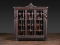 An Aesthetic Movement Crane and Mask Carved Mahogany and Glass Paneled Bookcase