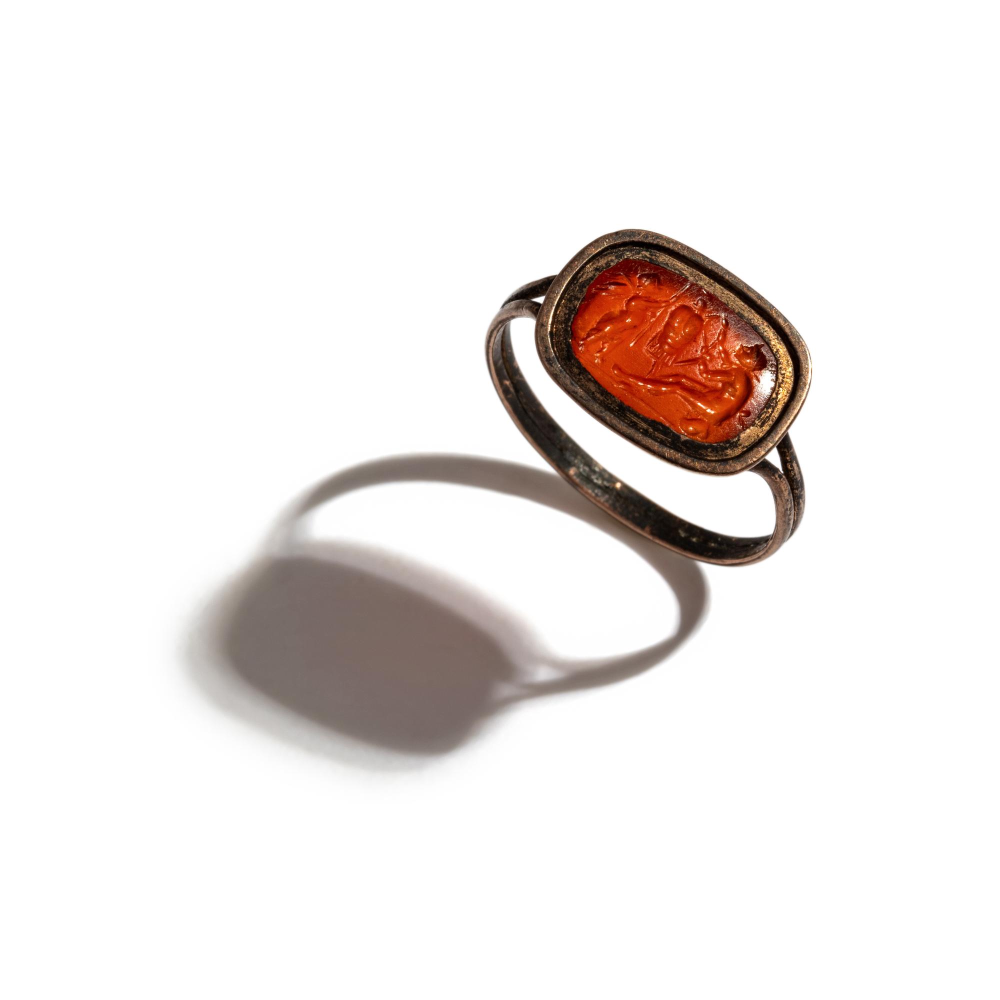 A Roman Carnelian Ring Stone with the God Eros Beside a Tropaion — Set in a gilt-copper ring