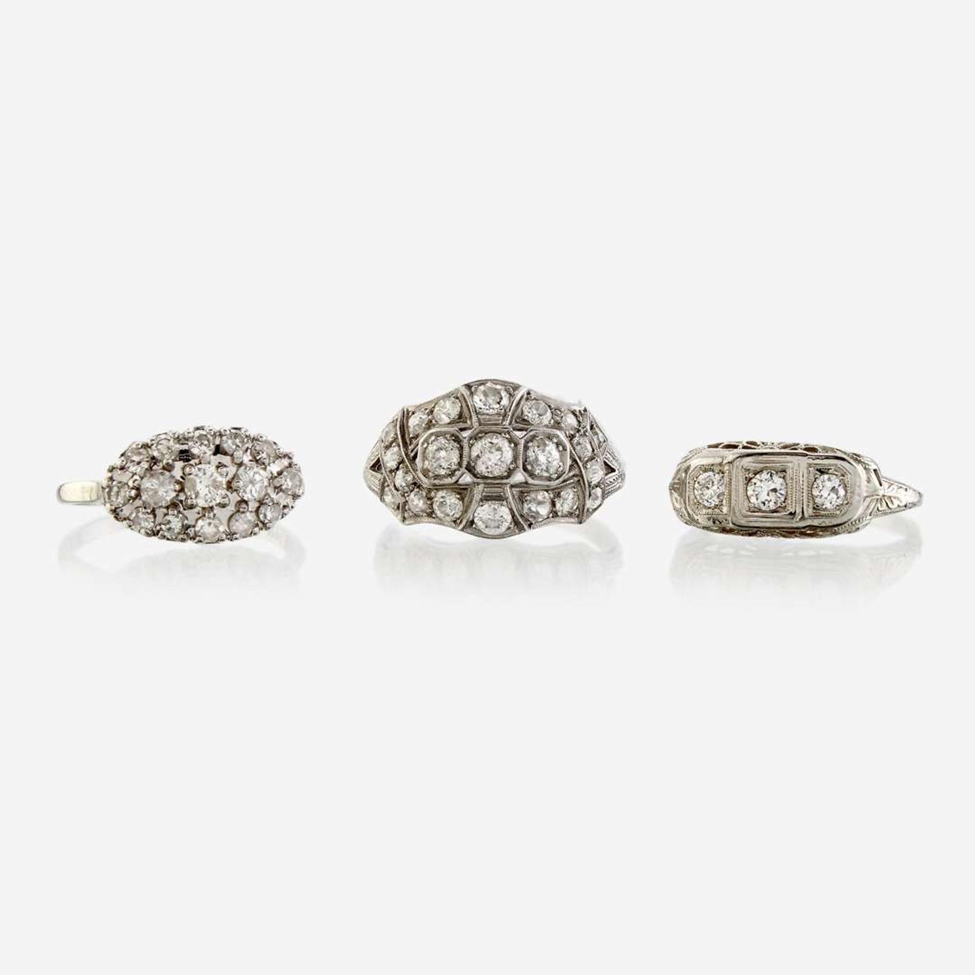 A collection of three white metal and diamond rings