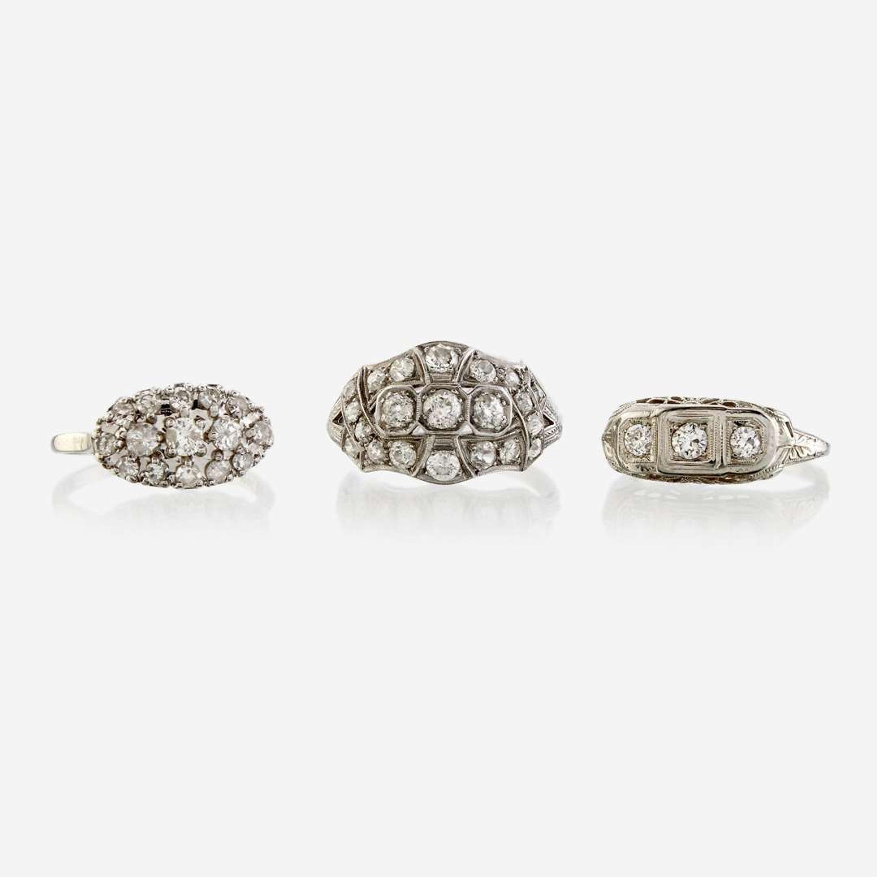 A collection of three white metal and diamond rings