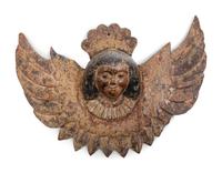 Two Continental Carved and Painted Winged Masks and an Ornament of a Putto Sleeping in a Shell