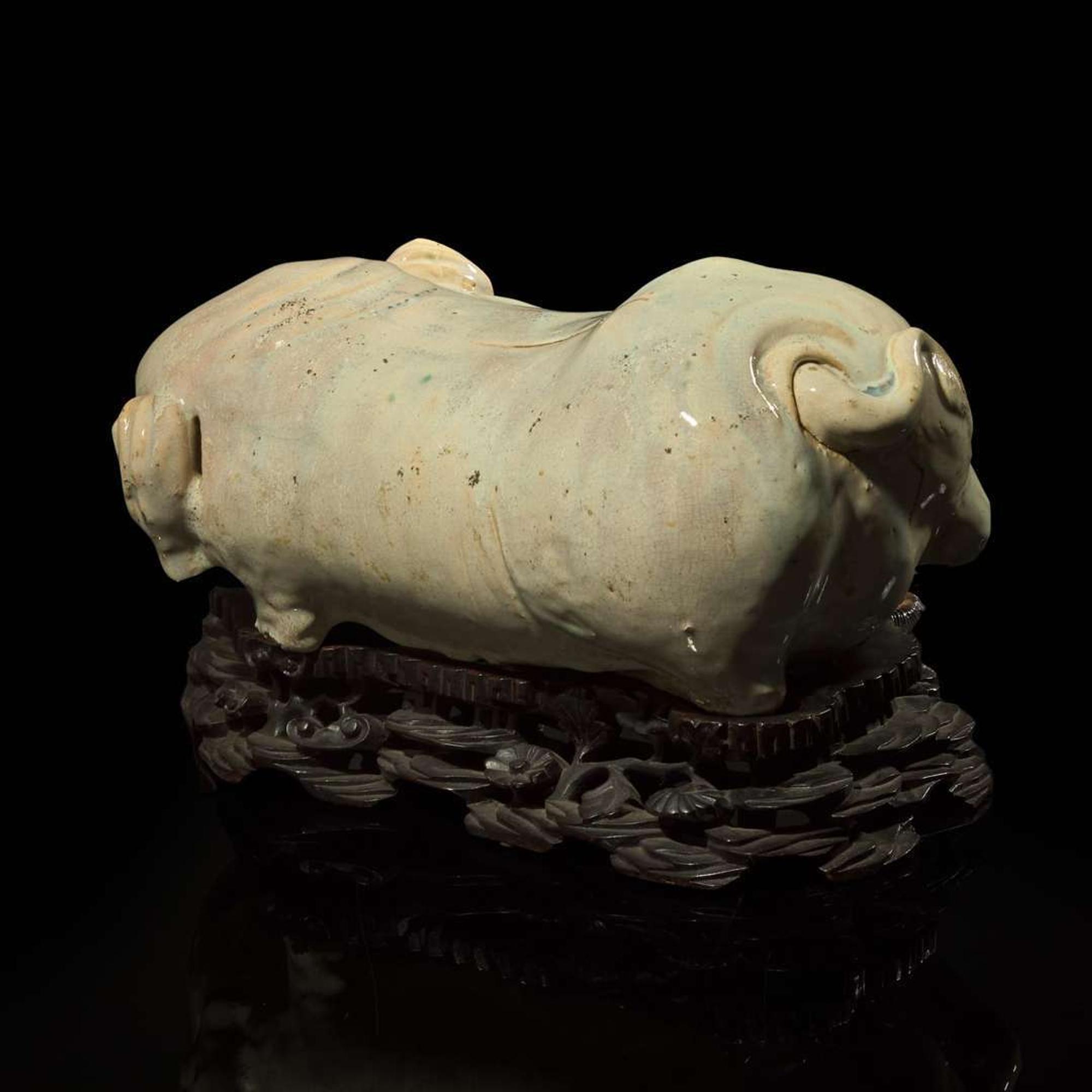 An unusual Chinese elephant-form white-glazed stoneware pillow and carved wood base 白象瓷枕與木座