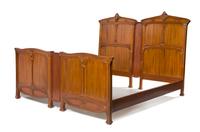 Louis Majorelle, (French, 1859-1926), a bedroom set, comprising an armoire separated into two individual display cabinets, two twin hea