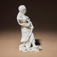 A Chinese Blanc-de-Chine Porcelain Standing Figure of a Luohan, Qing Dynasty — 清 德化白瓷羅漢立像