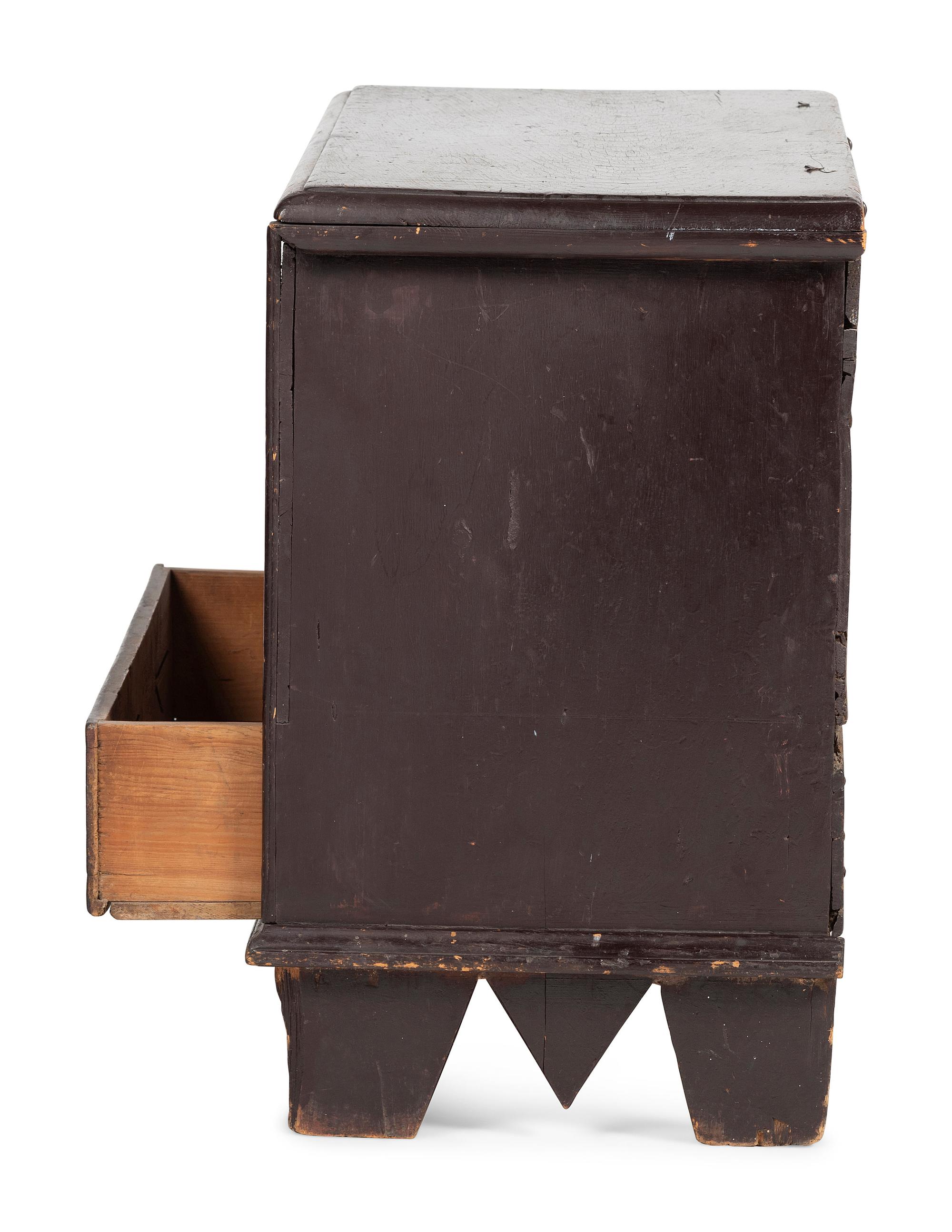 A Rare Pilgrim Century Black Painted Pine One-Drawer 'M' Chest