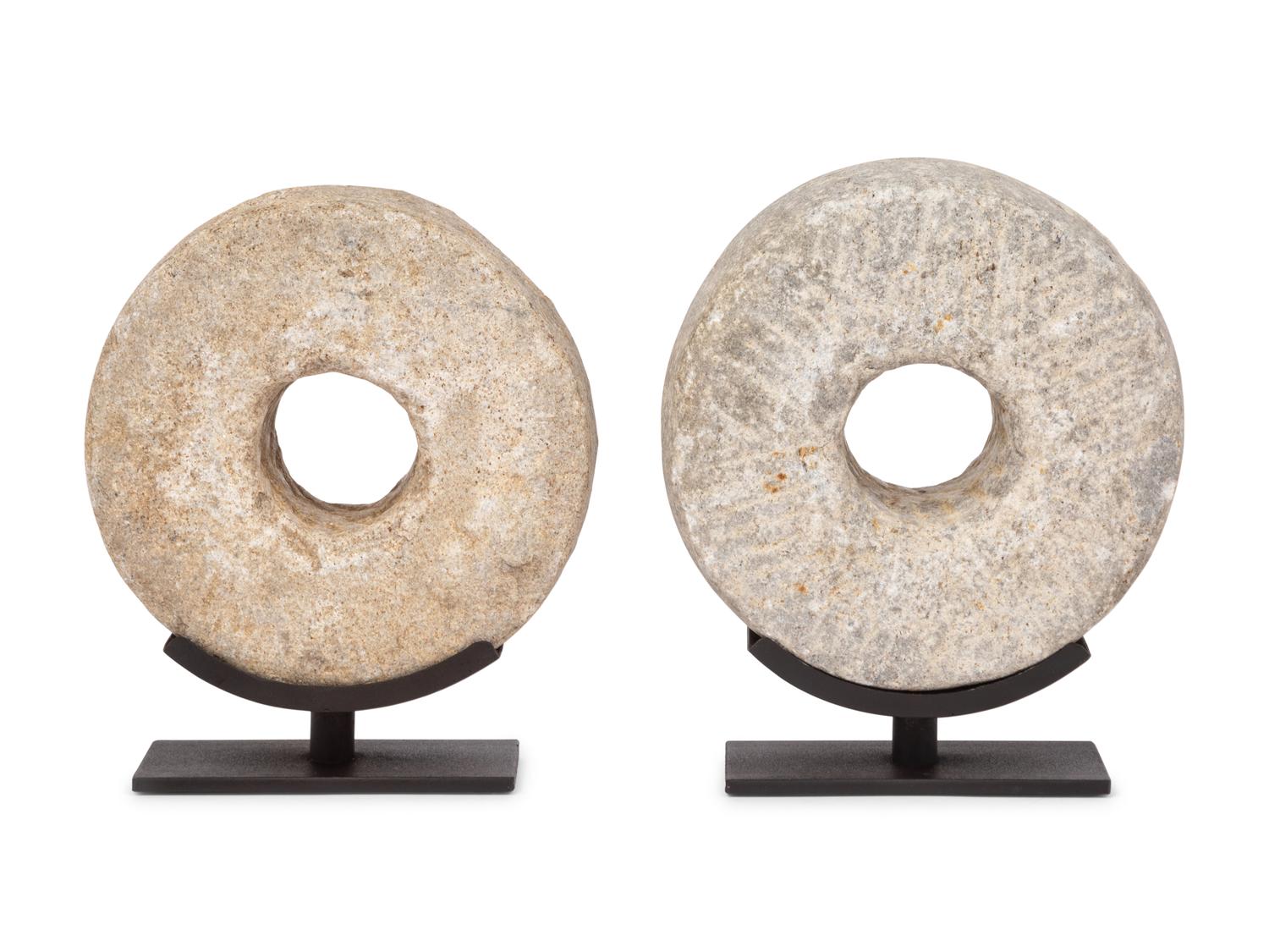 Two Millstone Disks on Metal Stands