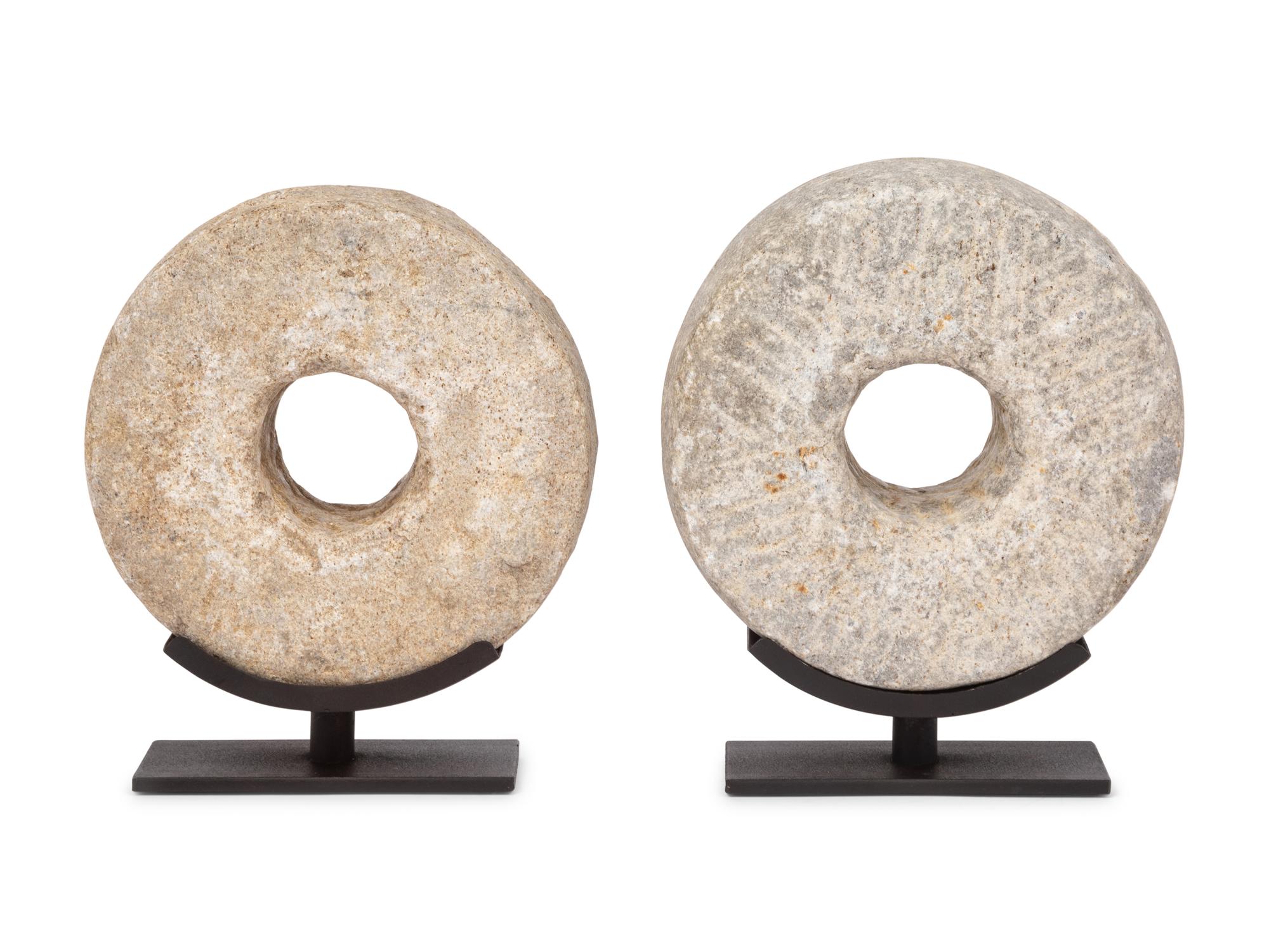 Two Millstone Disks on Metal Stands