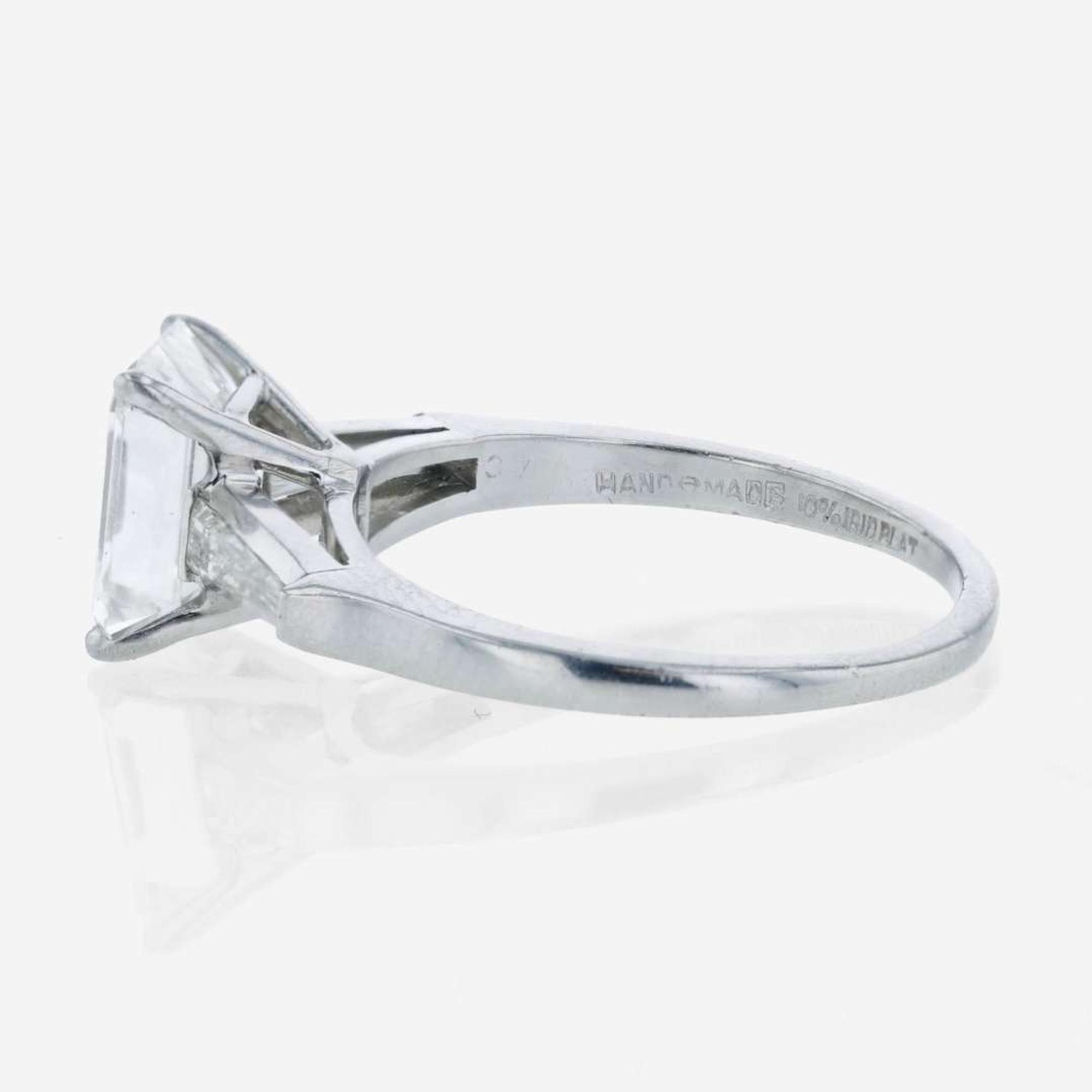 An emerald-cut diamond accented solitaire ring