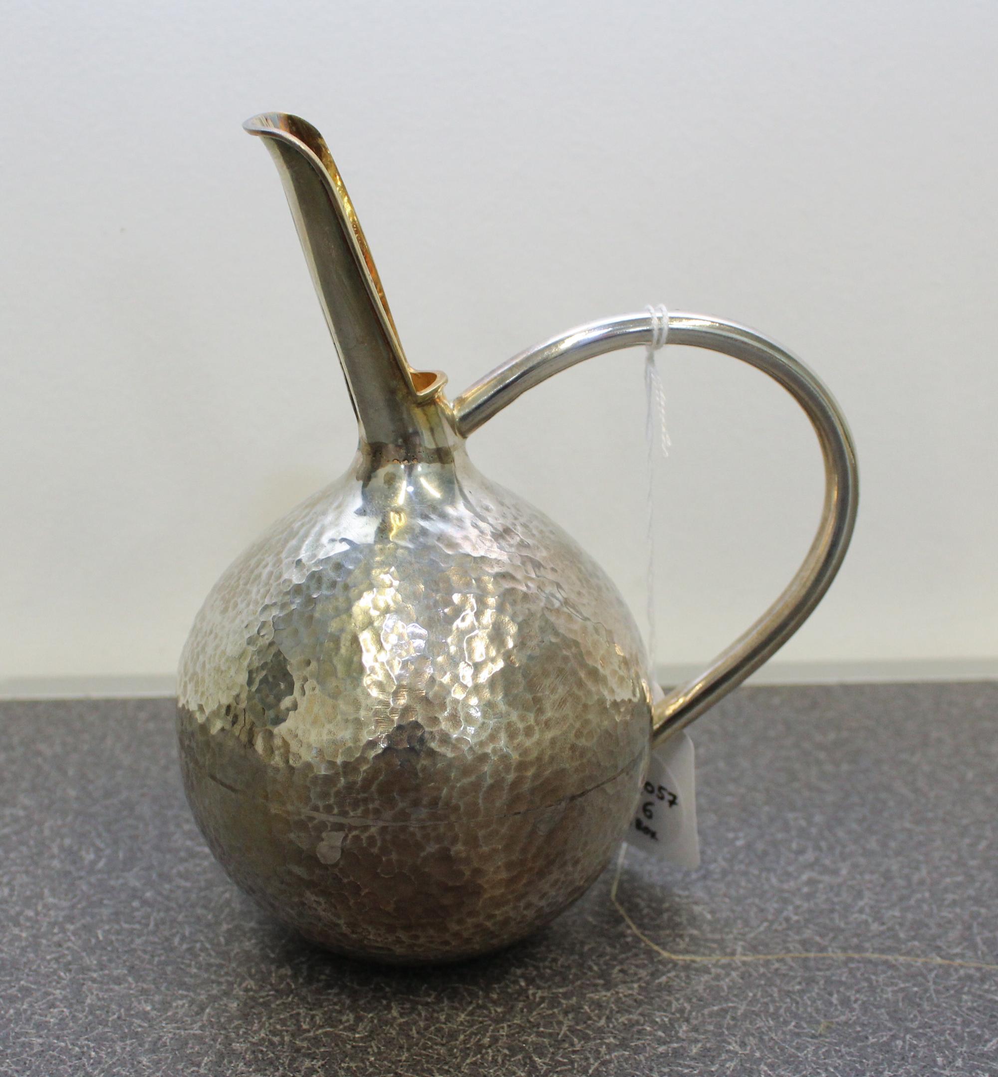 A Greek Silver Wine Jug, Michalas, Athens, the body of globular form with a spot hammered finish having a handle connecting to a gilt-s