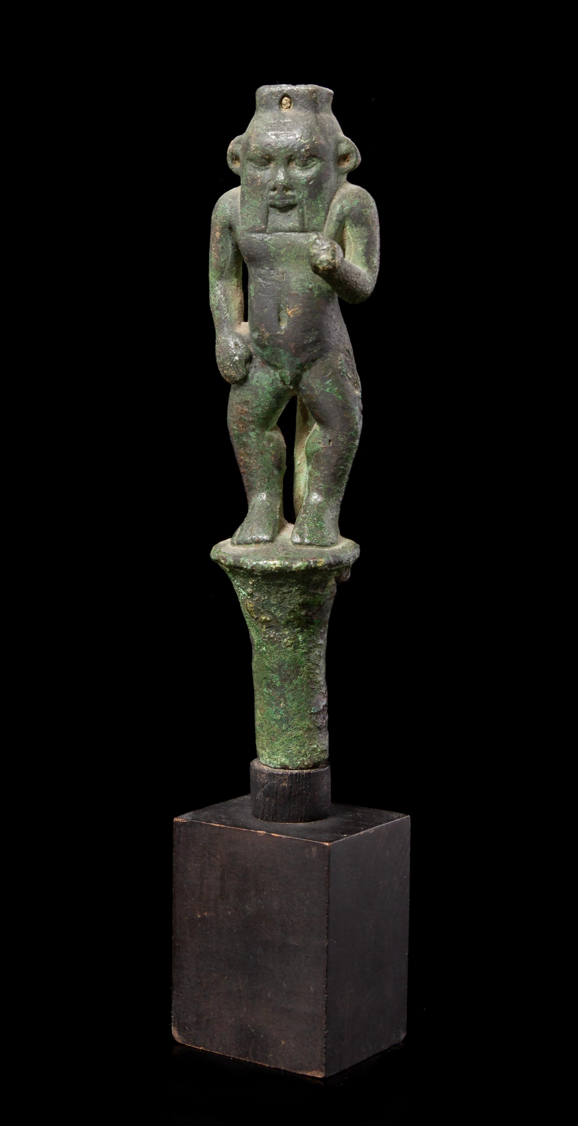 An Egyptian Bronze Bes Standing on a Papyrus Umbel Height 7 inches. — THIRD INTERMEDIATE PERIOD, DYNASTY 21-22, 1070-712 B.C.E.
