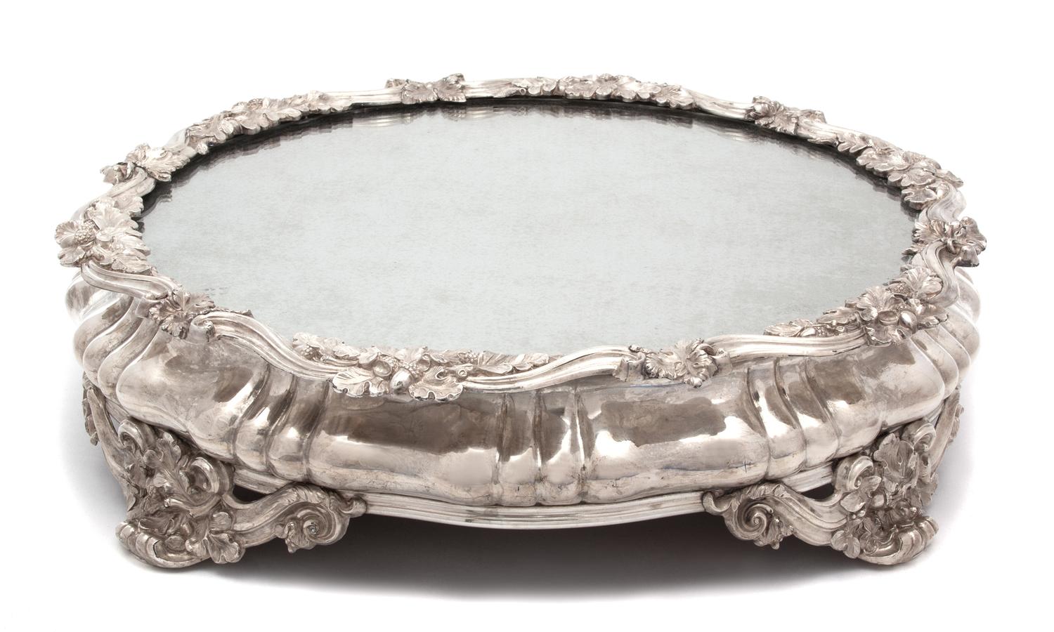 A Continental Silver Plate Mirror Top Plateau, 19TH CENTURY, having scrolll and oak leaf border and feet.