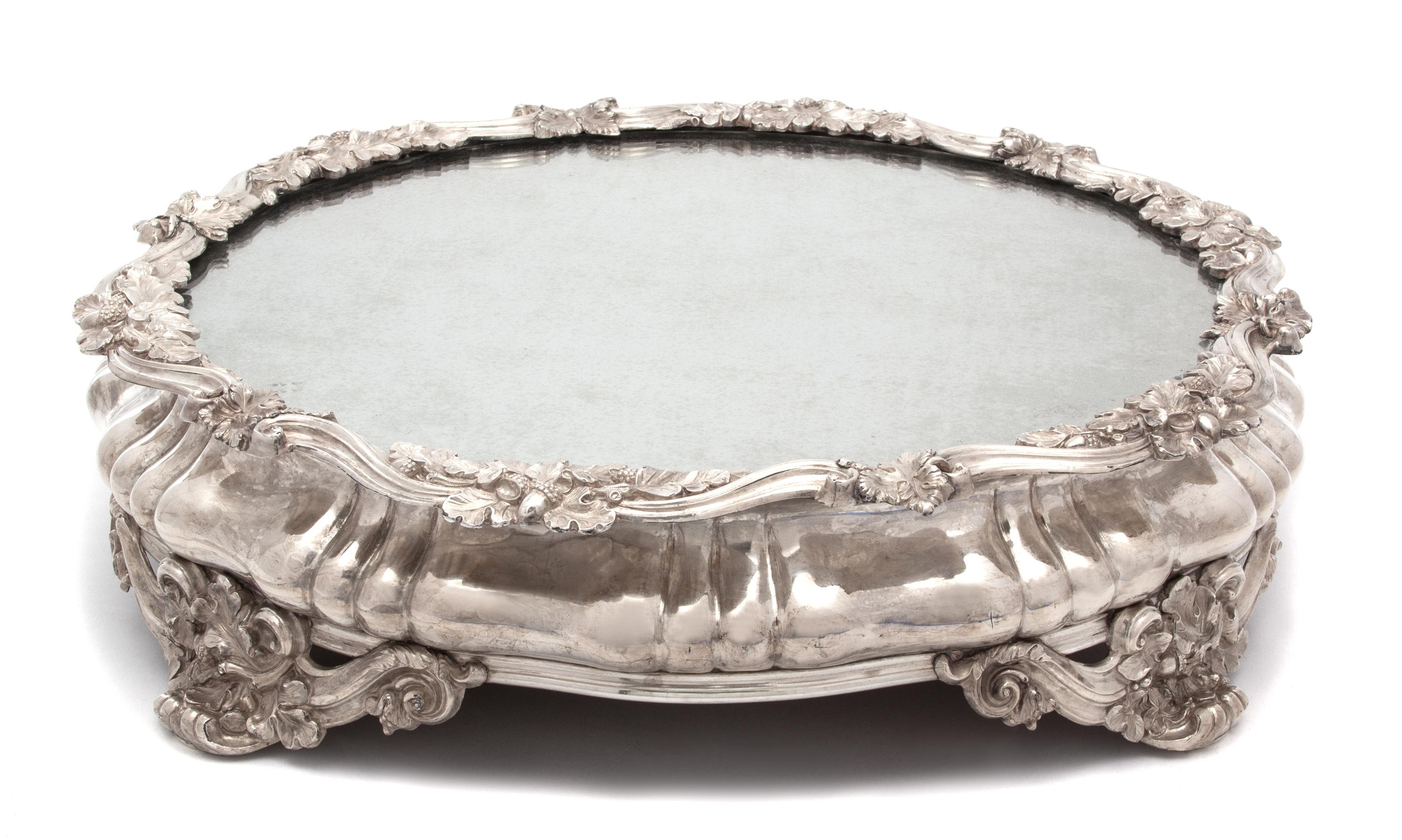 A Continental Silver Plate Mirror Top Plateau, 19TH CENTURY, having scrolll and oak leaf border and feet.