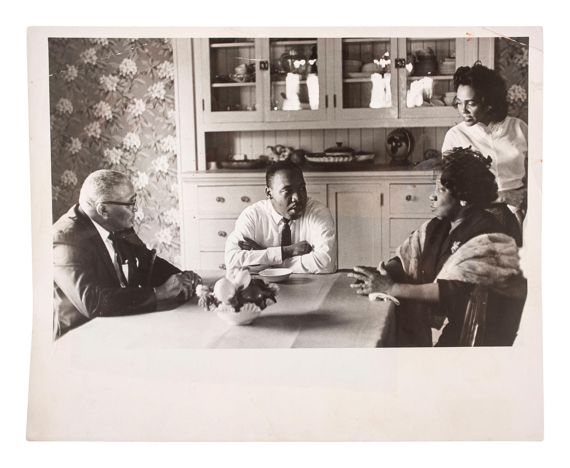 [KING, Martin Luther, Jr. (1929-1968)]. Press photograph of Dr. Martin Luther King, Jr. deep in discussion with Coretta Scott King and his parents, Martin Luther King, Sr. and Alberta King. 10 May 1964.
