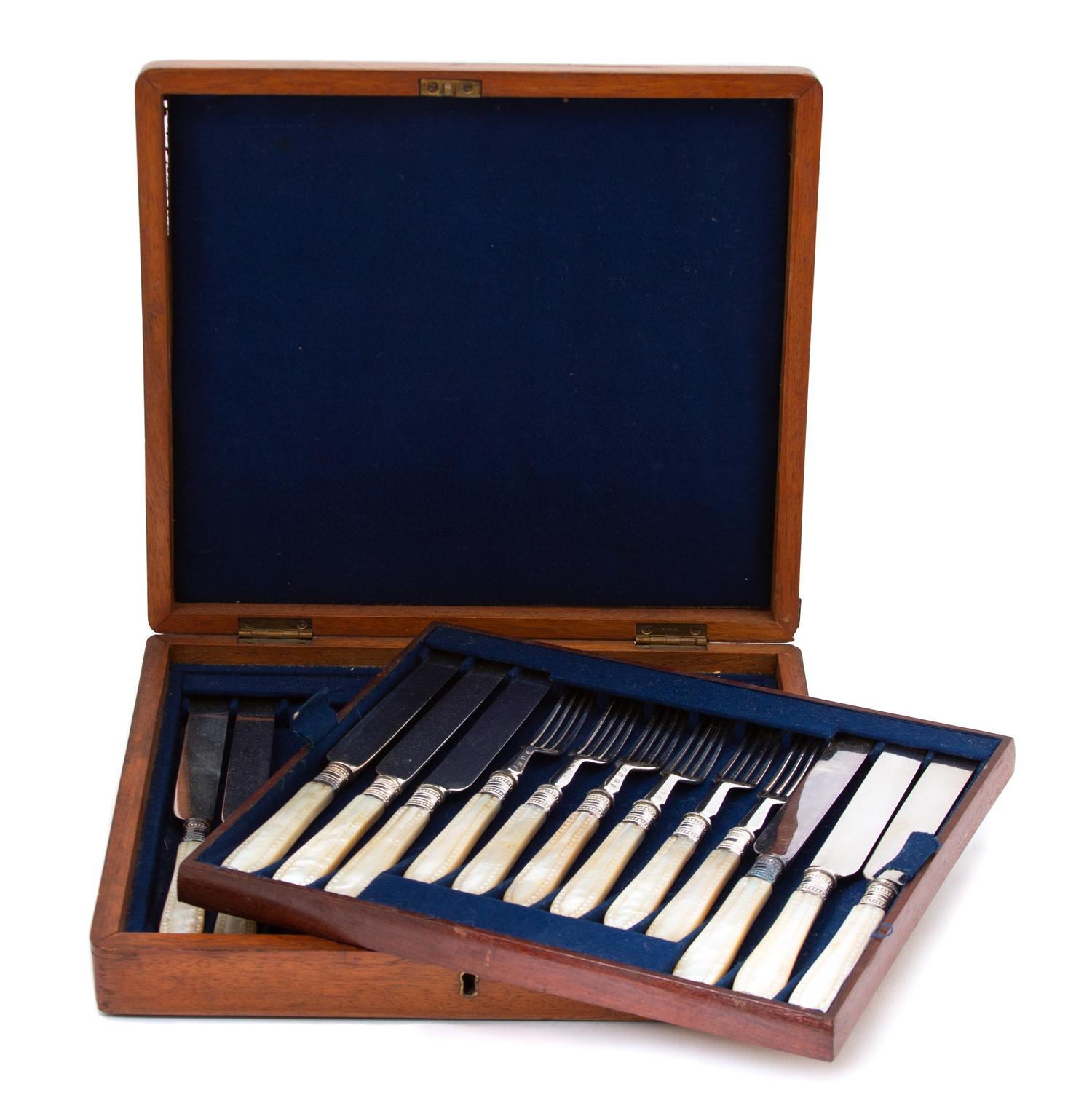 A 23-Piece Silver Plate and Carved Mother of Pearl Dessert Set, 19TH CENTURY, comprising 11 knives and 12 forks in a burlwood case.