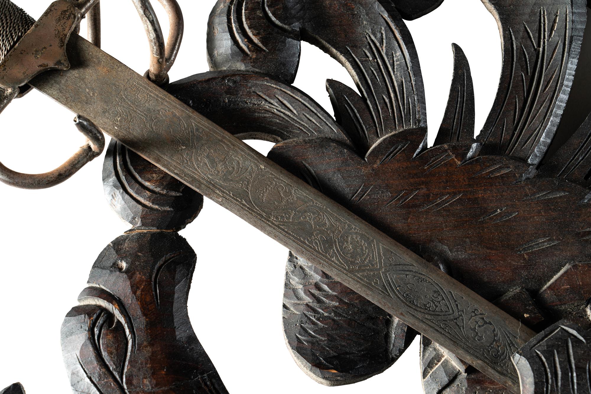 A Continental Carved Walnut Coat-of-Arms Plaque with Metal Crossed Swords