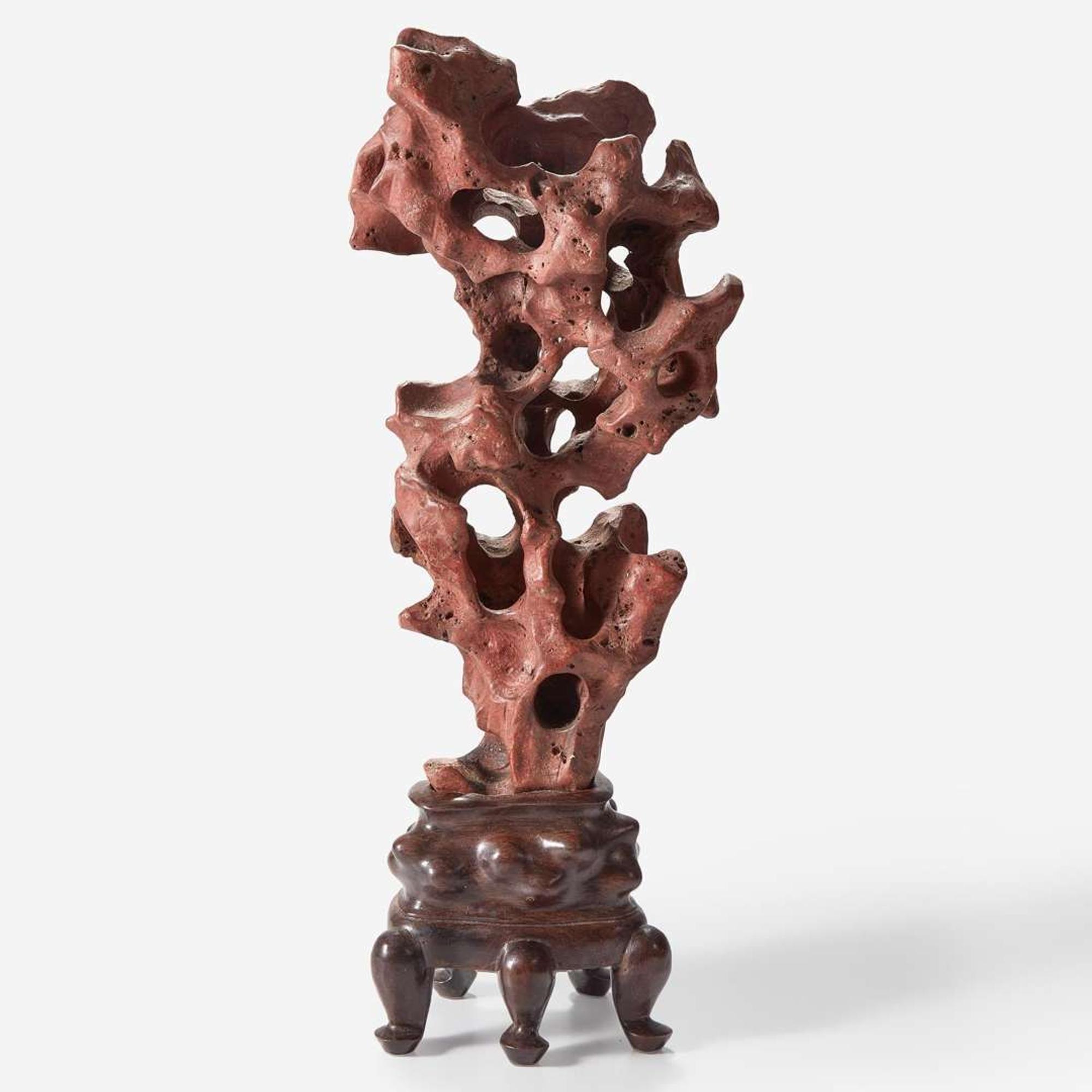 A Chinese scholar's rock on wood stand, possibly red Taihu stone