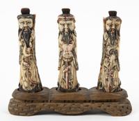 Three Carved Bone Figures Width of stand 8 inches.