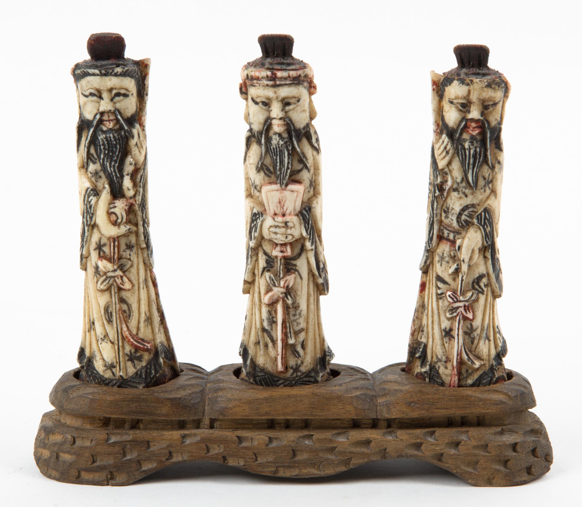 Three Carved Bone Figures Width of stand 8 inches.