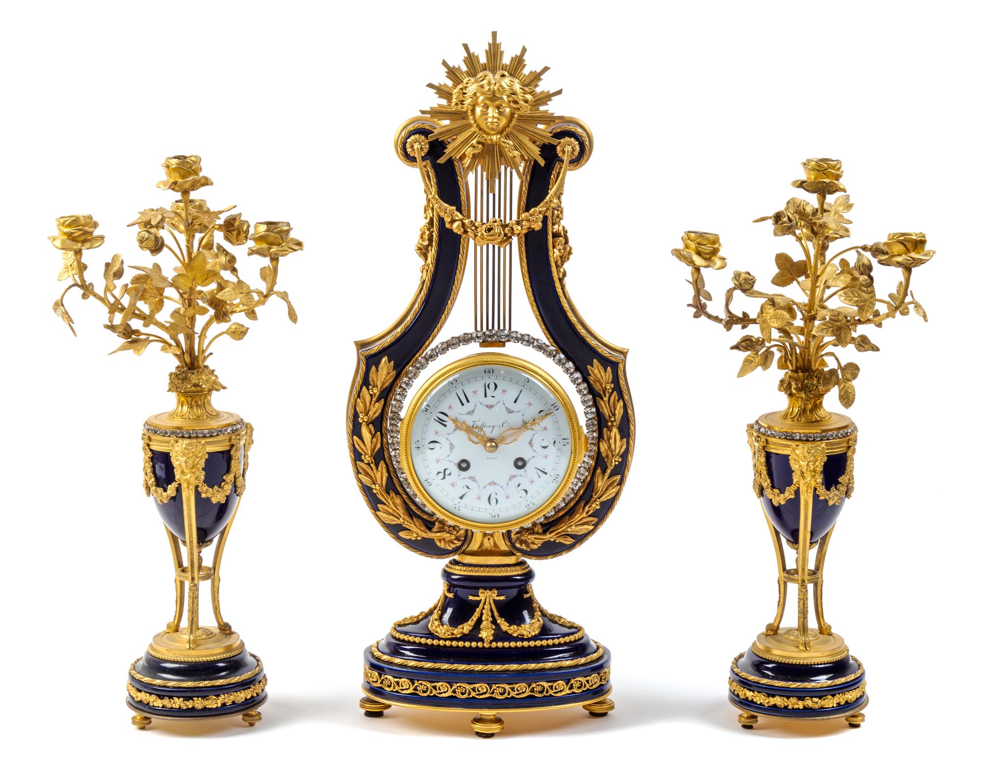A French Gilt Bronze and Porcelain Clock Garniture Height of mantel clock 22 1/2 inches. — CIRCA 1900, RETAILED BY TIFFANY & CO.