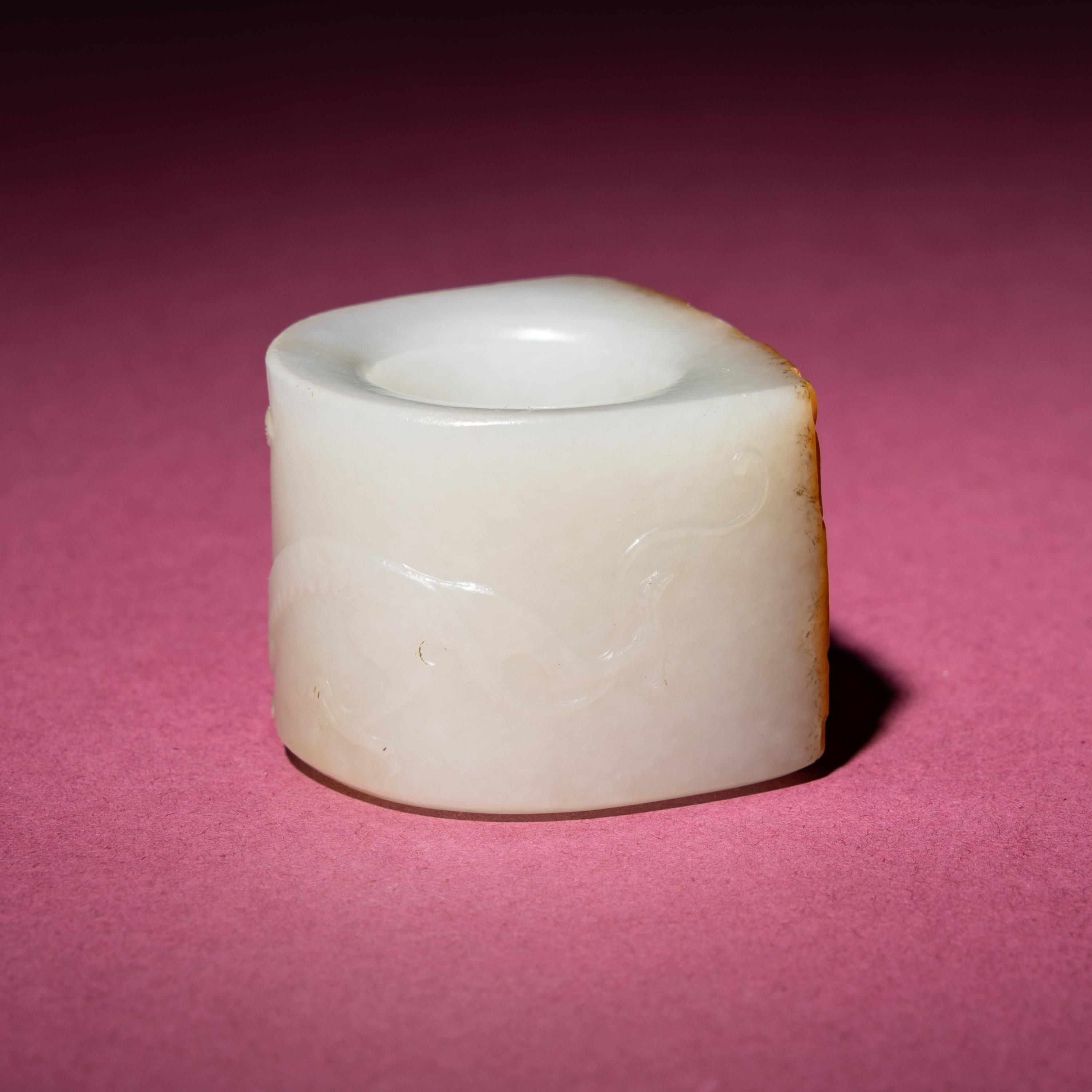 A Chinese Russet and White Jade 'Taotie and Chilong' Archer's Ring, 18th Century — 清中期 白玉留皮饕餮螭龍紋扳指