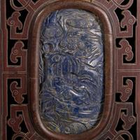 A Chinese Carved Lapis Lazuli Oval "Deer and Pine" Panel, Qing Dynasty — 清 硬木嵌青金石“鹿鶴同春”圖牌