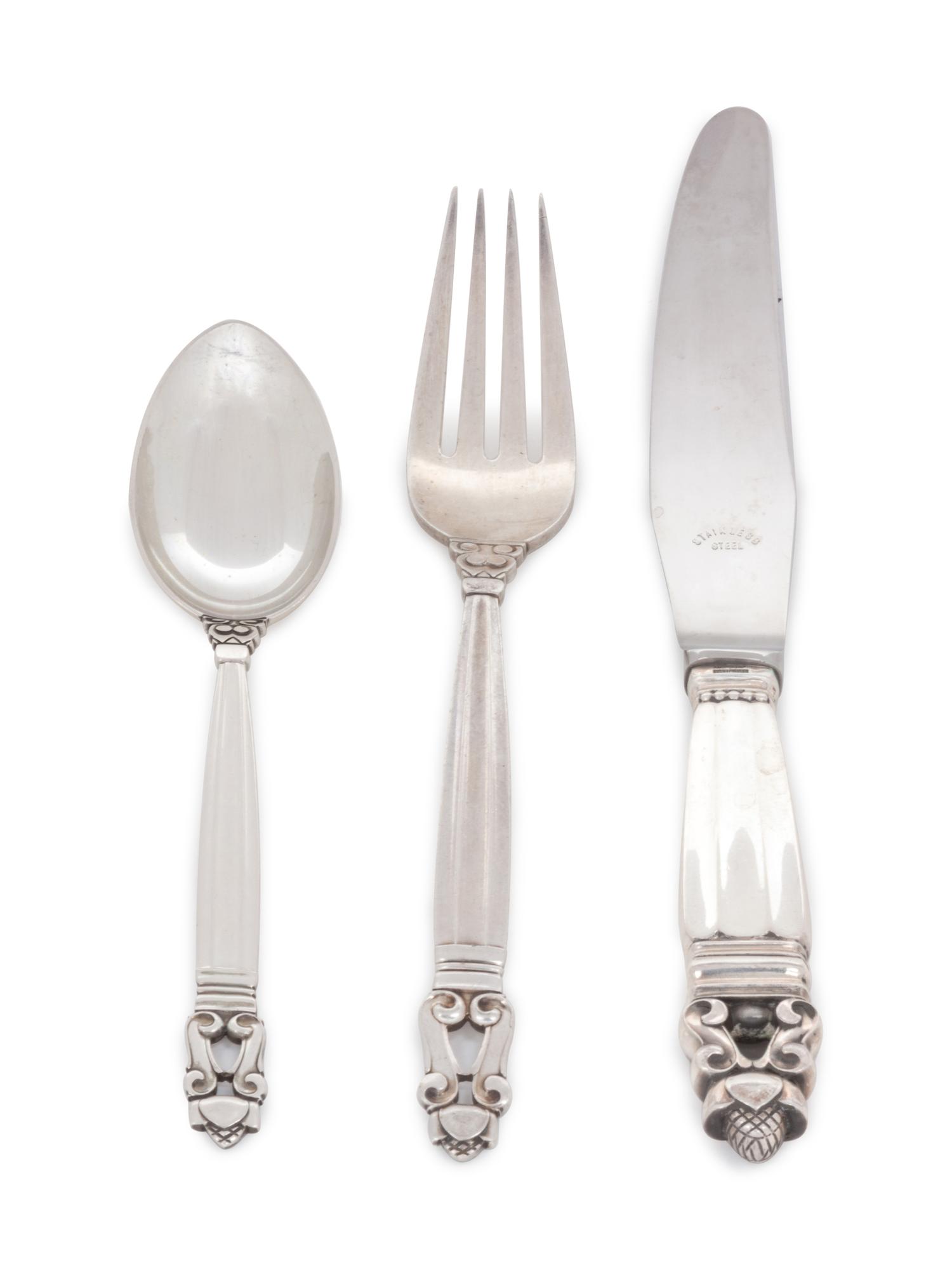 in the Acorn pattern, comprising: 6 dinner knives with stainless steel blades 6 butter spreaders 1 cake knife with stainless steel blade 6 dinner forks 6 salad forks 7 cocktail forks 6 tablespoons 1 teaspoon 5 smaller teaspoons 6 soup spoons 6 demitasse spoons 56 pieces total.