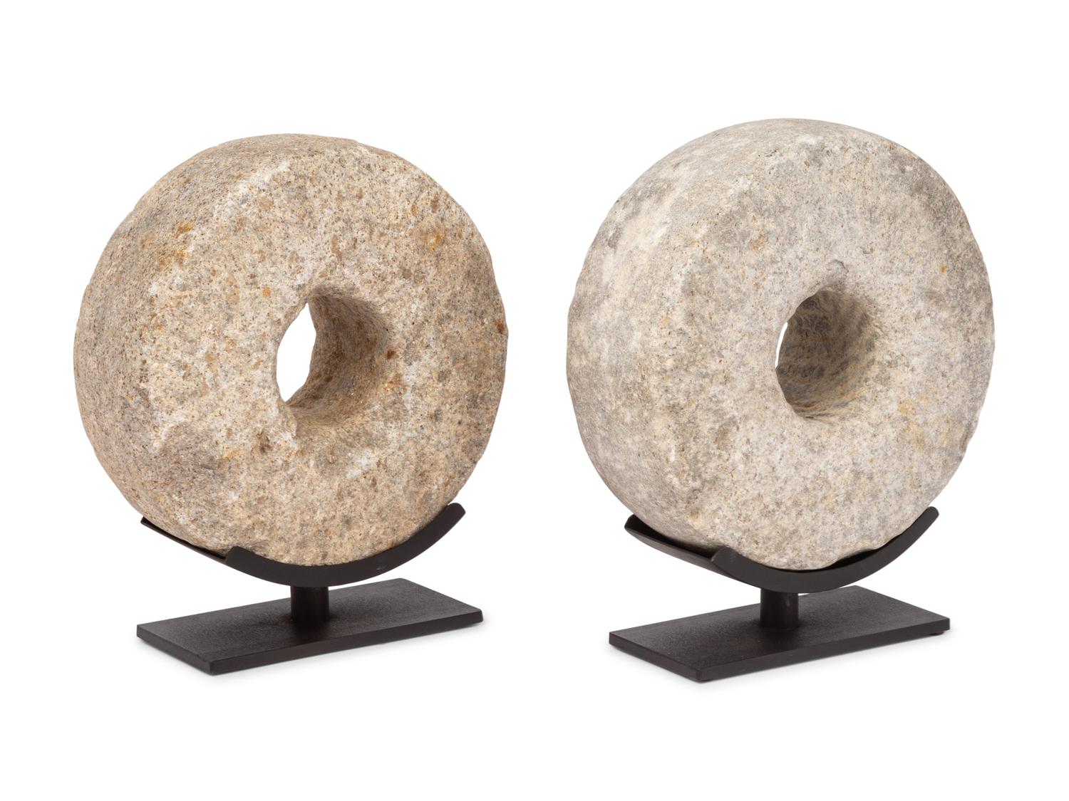 Two Millstone Disks on Metal Stands