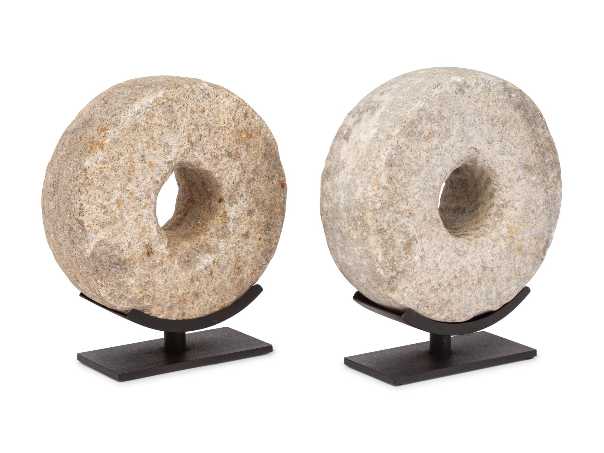 Two Millstone Disks on Metal Stands