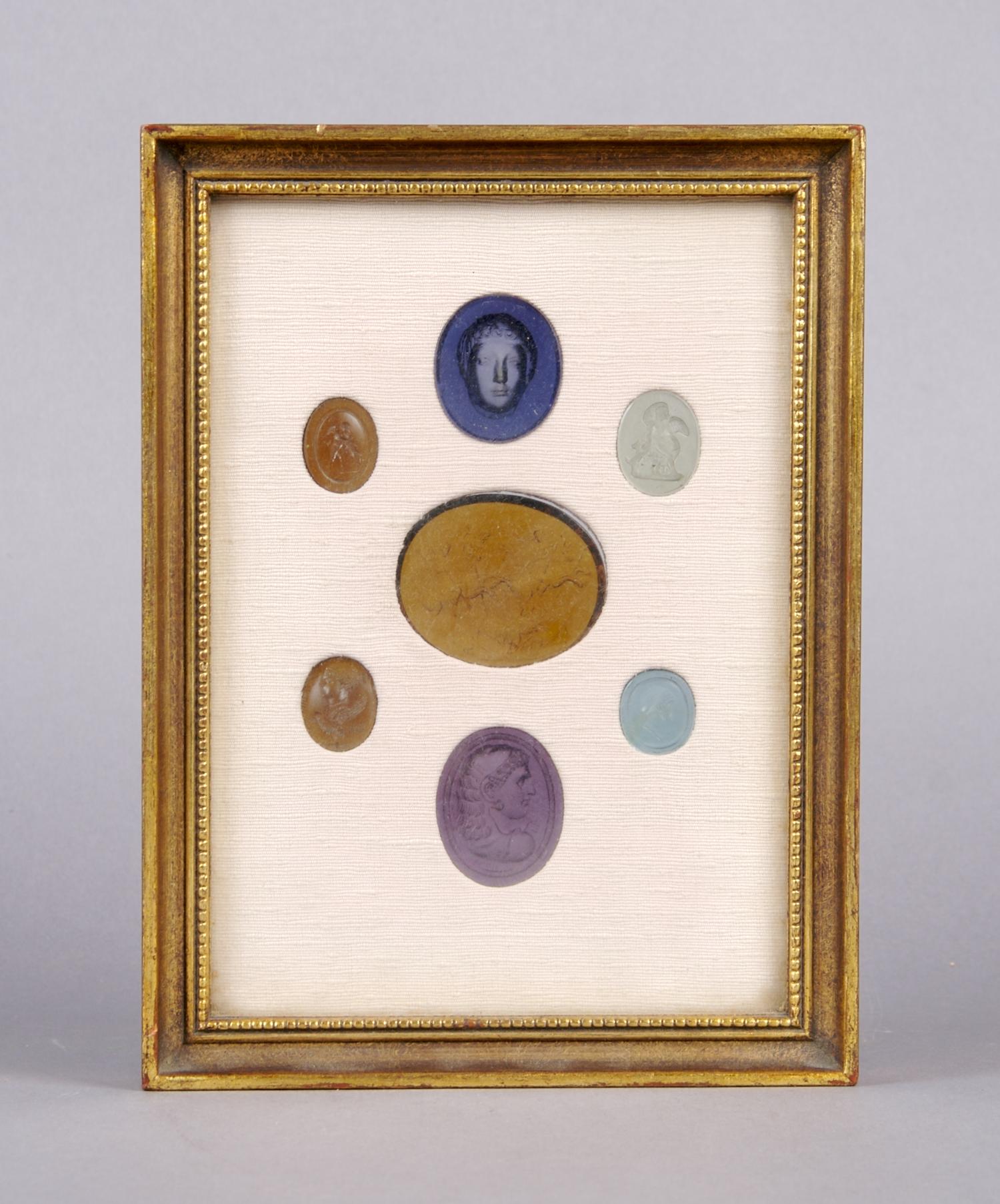 A Collection of Seven Glass Intaglios, Height of frame overall 7 3/4 inches.