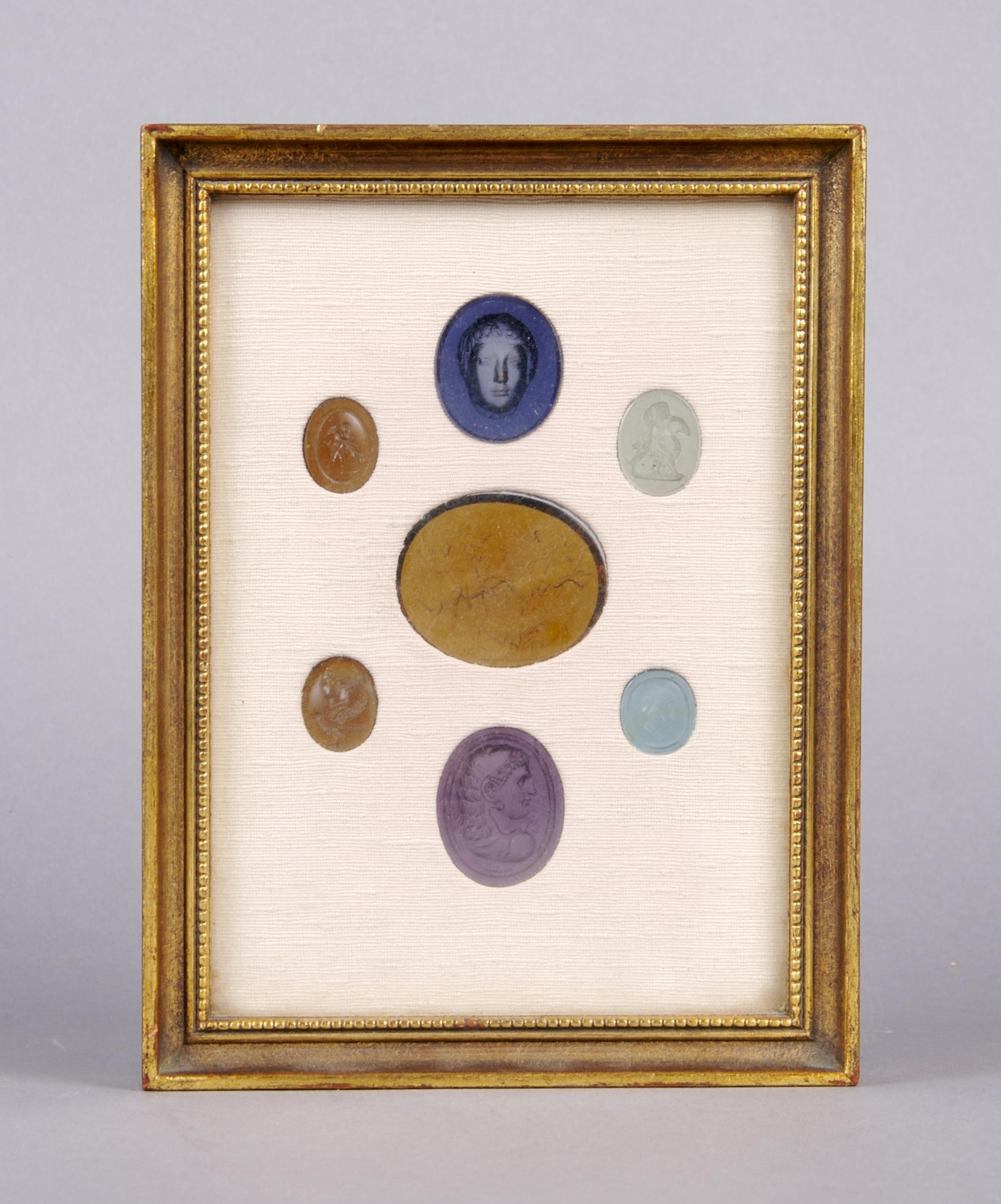 A Collection of Seven Glass Intaglios, Height of frame overall 7 3/4 inches.