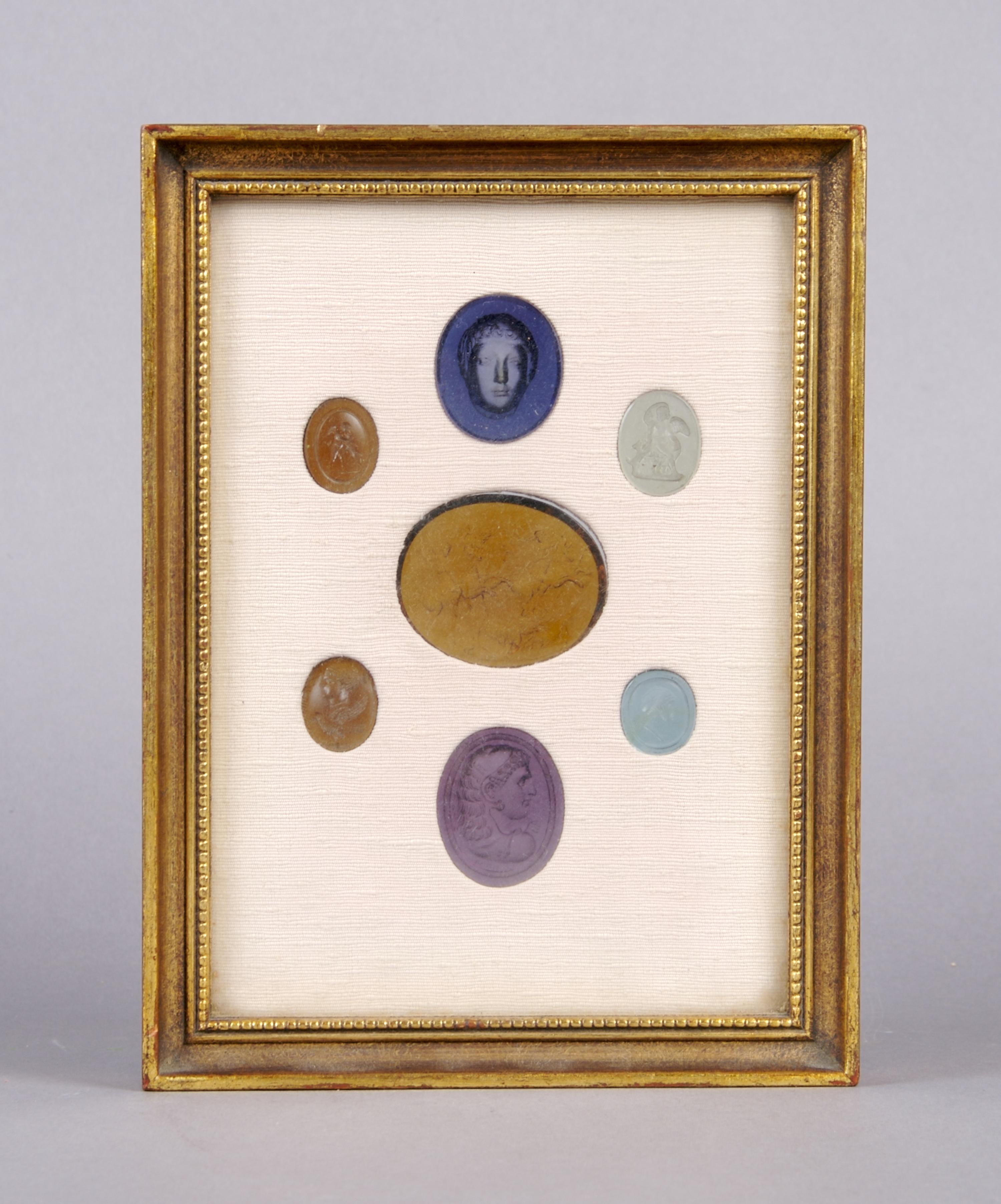 A Collection of Seven Glass Intaglios, Height of frame overall 7 3/4 inches.