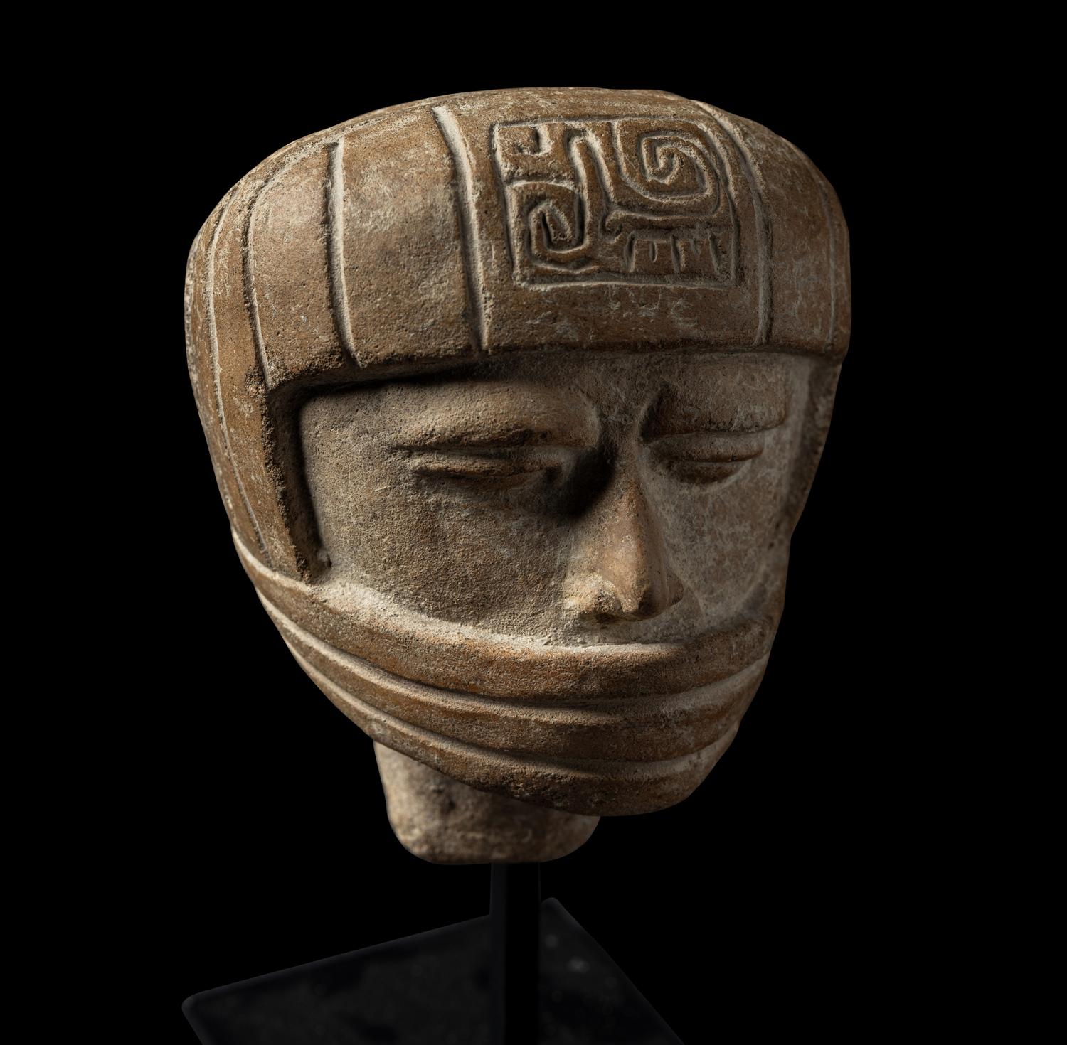 A Veracruz Terracotta Head Wearing a Helmet with an Incised Glyph