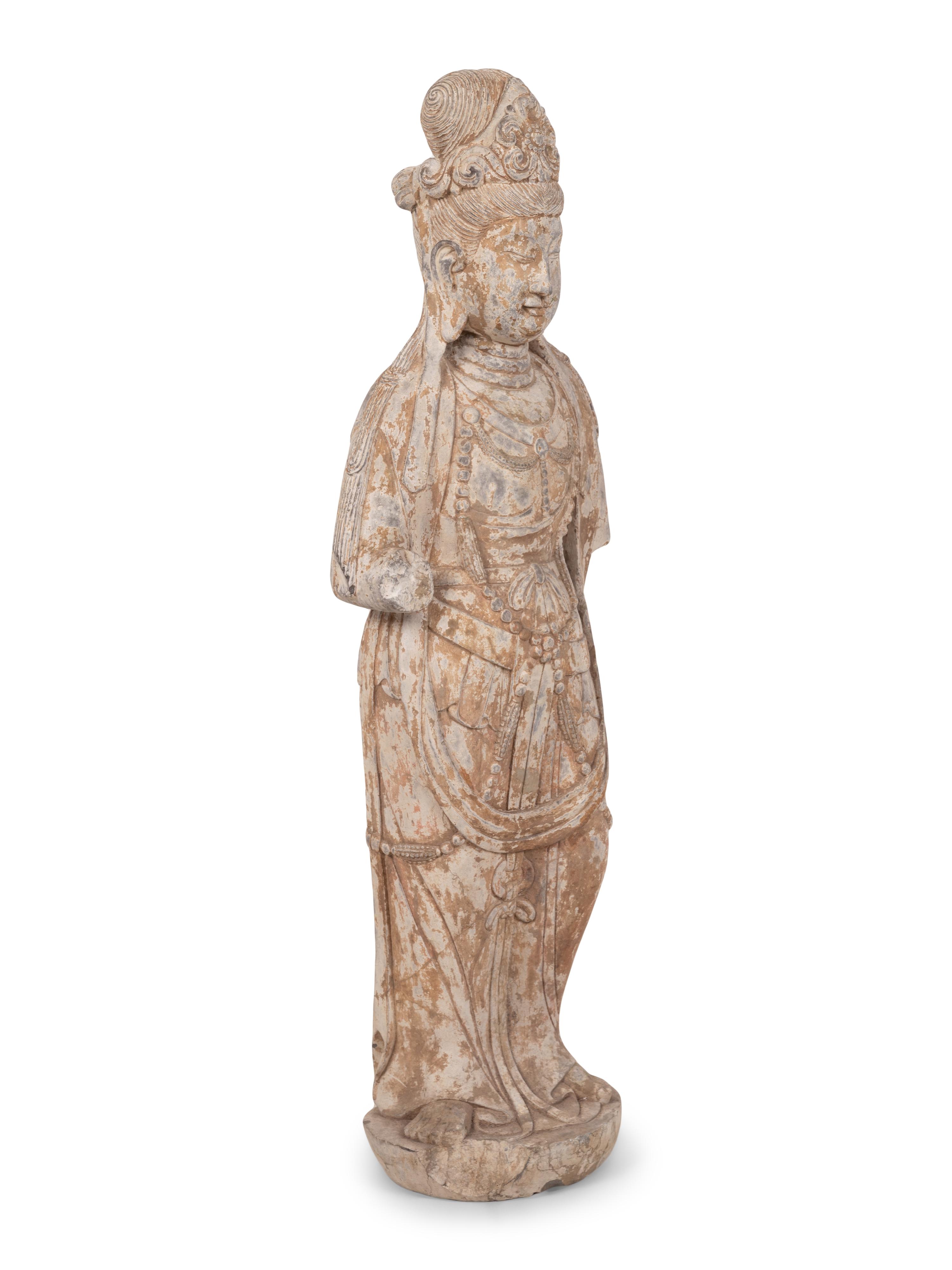 A Chinese Carved Stone Standing Guanyin Figure with Remnants of Polychrome Decoration