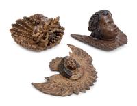 Two Continental Carved and Painted Winged Masks and an Ornament of a Putto Sleeping in a Shell