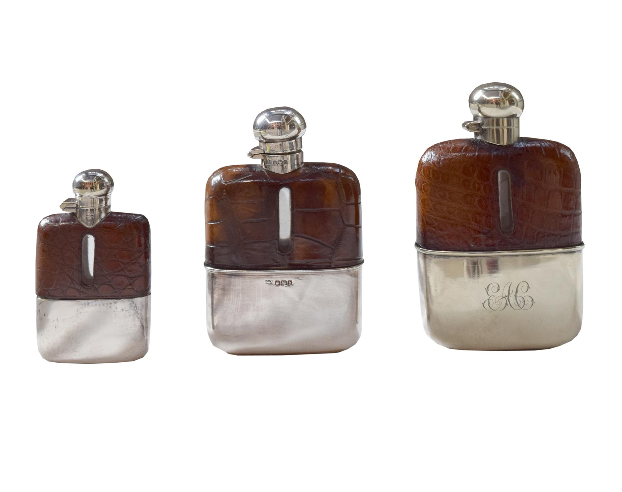 A Set of Three Silver and Stamped Leather Hip Flasks Left: 2.25" x .5" x 3.75" tall: Middle: 3" x 1" x 5" tall: Right: 3.25" x 1" x 5.5 — England, Circa 1925-1940