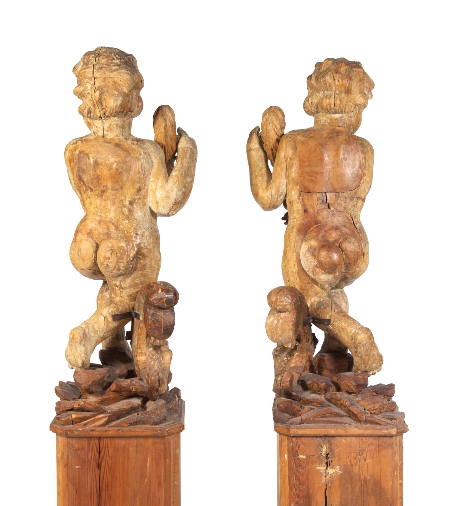 A Pair of Florentine Carved Walnut Figures of Putti on Plinths