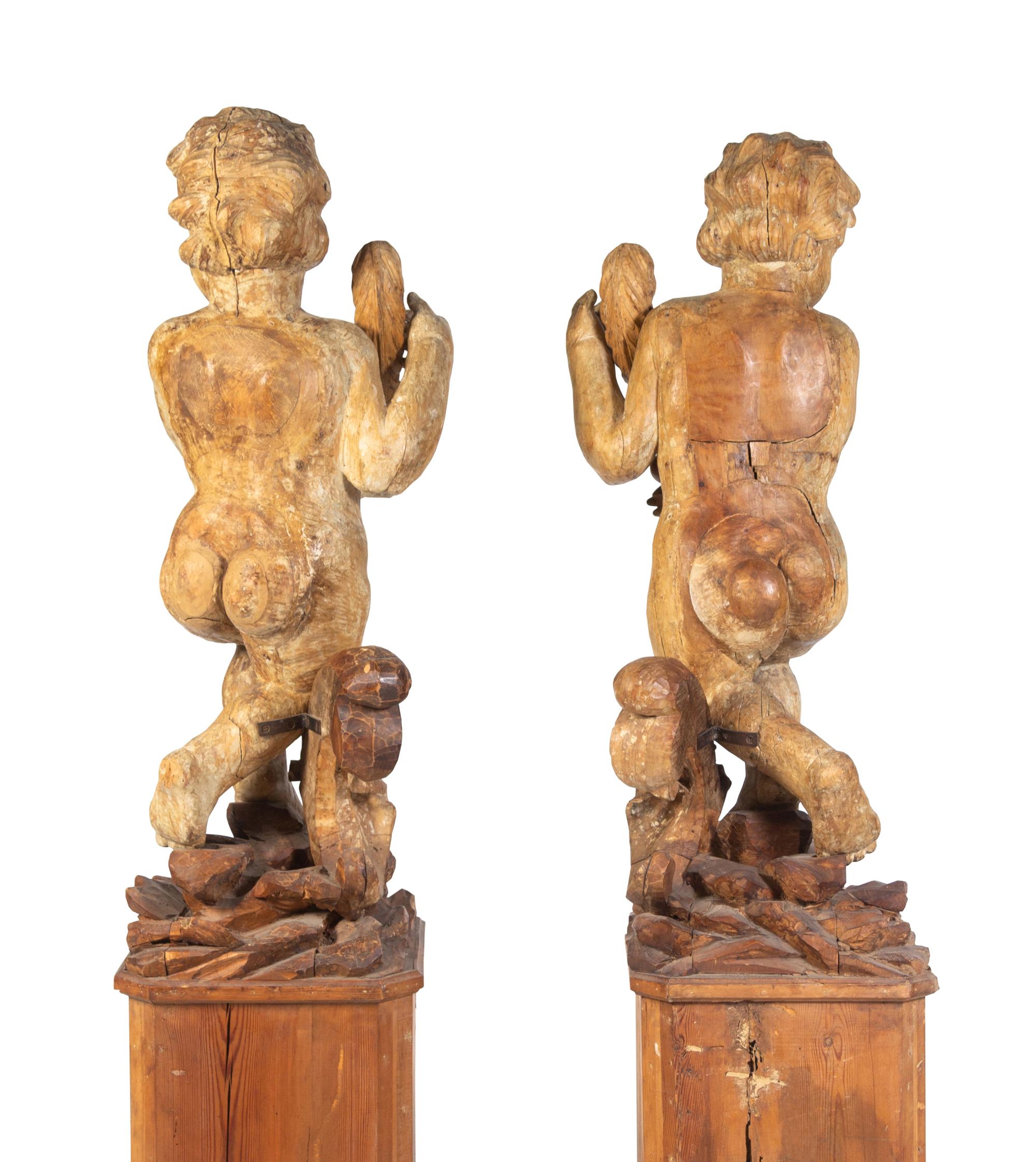 A Pair of Florentine Carved Walnut Figures of Putti on Plinths