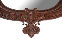 A Carved Mahogany Oval Mirror with Opposing Griffins