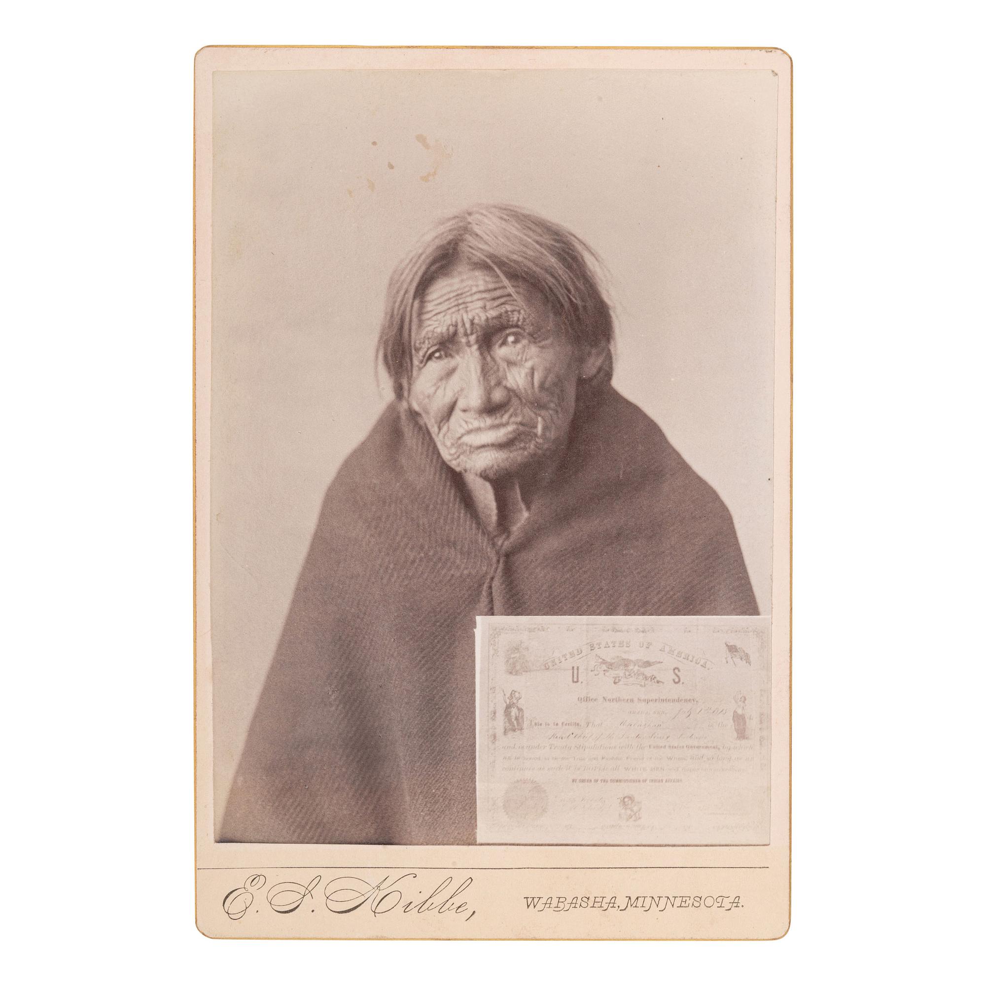 [NATIVE AMERICANS]. Cabinet photograph of aged Sioux woman with image of US Treaty document. Wabasha, Minnesota: E.S. Kibbe, [ca 1885].
